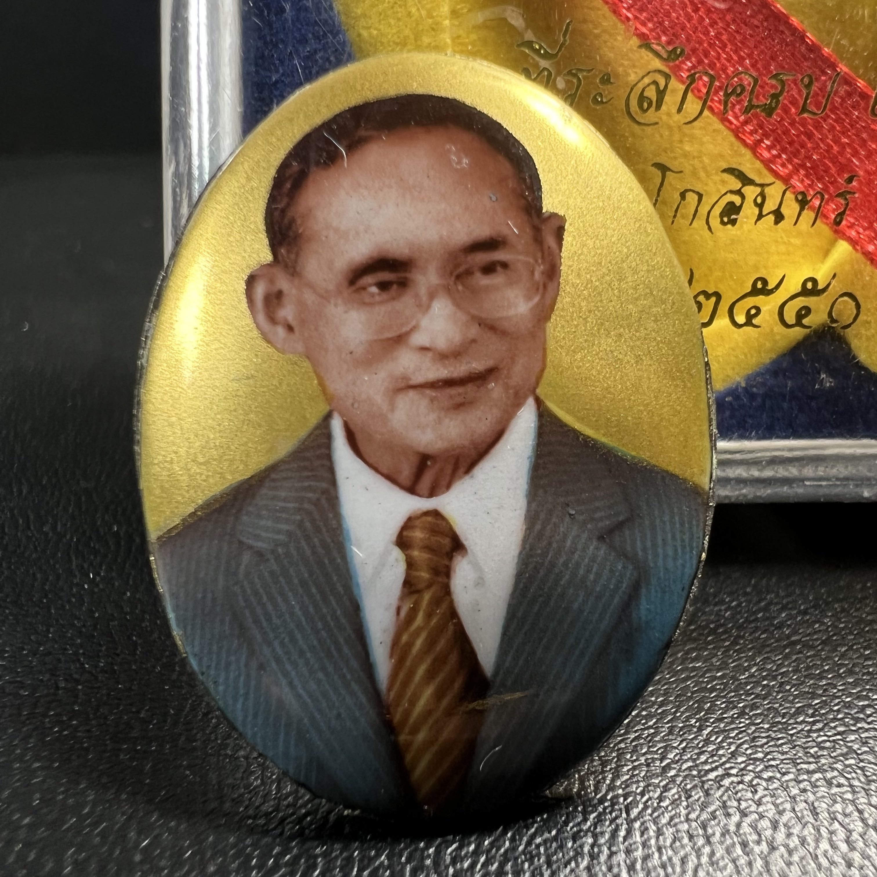 ล็อกเกตในหลวงรัชกาลที่9 ที่ระลึกครบ 25 ปี มูลนิธิศรีรัตนโกสินทร์ วัดสุทธาราม พ.ศ. 2550 พิมพ์ทรงวงรีรูปไข่เล็กฉากสีทอง หลังปิดแผ่นโลหะสีขาว(สแตนเลส)ฝังพระยอดธง(นิยม)