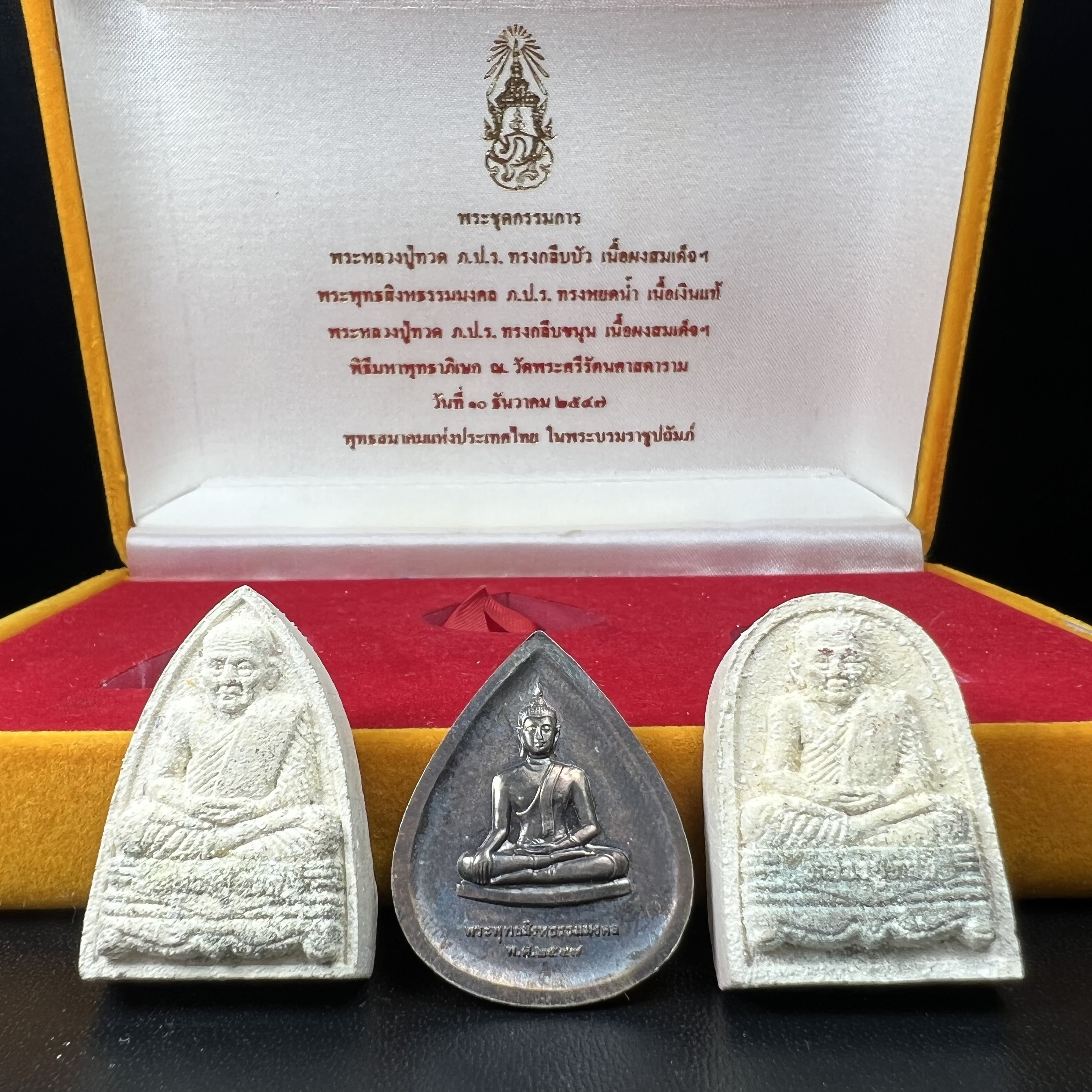 พระหลวงปู่ทวด ภปร.ปี2547 (เนื้อพิเศษกรรมการ)ทรงกลีบบัวและทรงกลีบขนุน เนื้อผงสมเด็จฯ(โรยผงตะไบ ชนวนเก่า) พร้อมเหรียญพระพุทธสิหธรรมมงคล ภปร. ทรงหยดน้ำ เนื้อเงินแท้ กล่องบรรจุเดิมครบ(1ชุด 3 องค์)(หายาก)