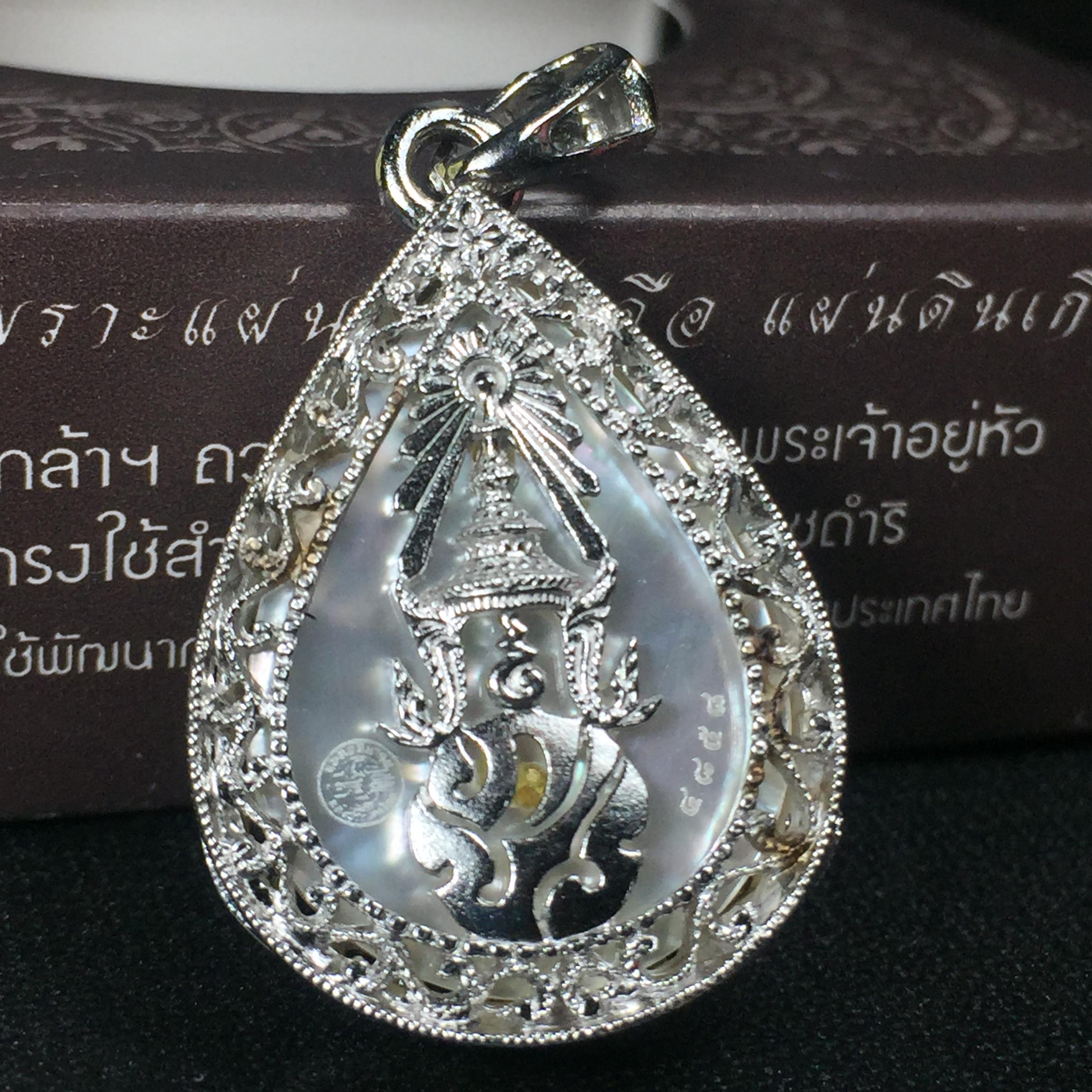 พระพุทธชินราช ภปร. โครงการ "เพราะแผ่นดินนี้ คือ แผ่นดินเกิด" ปี2548(รุ่นแรก) เหรียญทรงหยดน้ำ ขนาด 21 x 31 มม. เนื้อเงินสามกษัตริย์ องค์พระชุบสามกษัตริย์ ล้อมด้วยกรอบเงินชุบทองคำขาวสลักเสลาเป็นลวดลายละเอียดอ่อน ส่วนพื้นองค์พระเป็นเปลือกหอยมุข