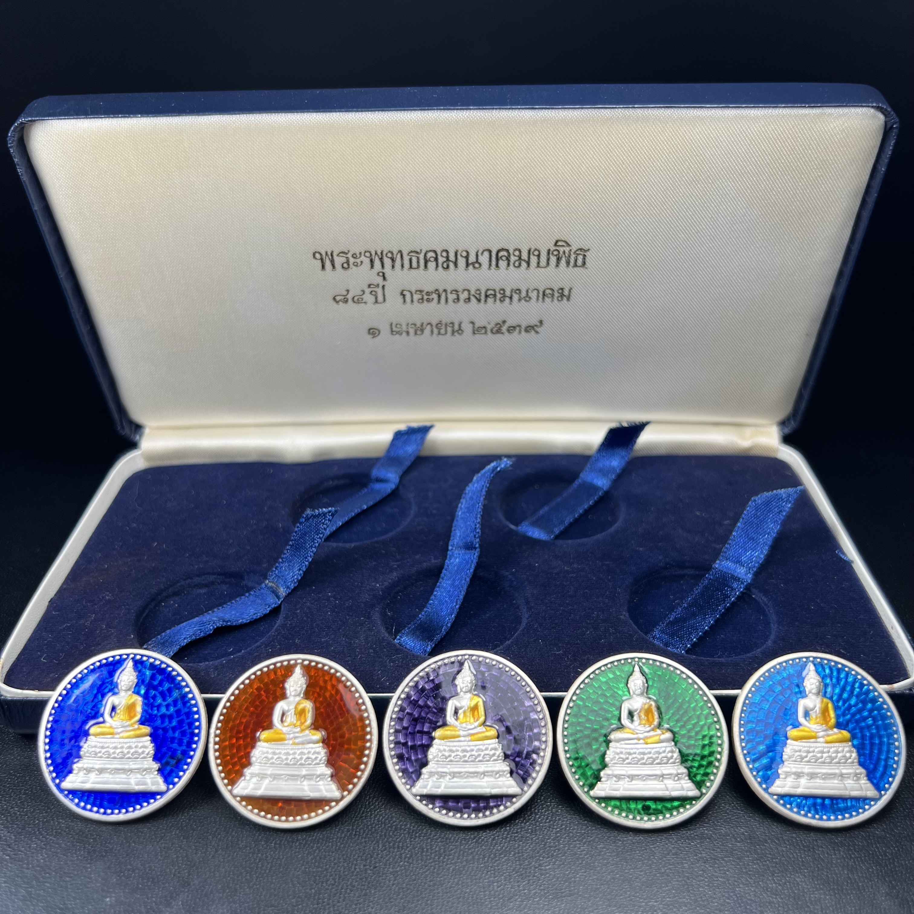 พระพุทธคมนาคมบพิธ (พระพุทธสิหิงค์จำลอง)(พระพุทธรูปประจำกระทรวงคมนาคม) หลังตรา ภปร. ครบรอบ 84 ปี กระทรวงคมนาคม พ.ศ.2539 ชุดเหรียญเนื้อเงินลงยา ขนาด 2.8 ซม. ครบชุดห้าสีพร้อมกล่องบรรจุเดิม ปลุกเสก ณ วัดพระแก้ว พิธีใหญ่