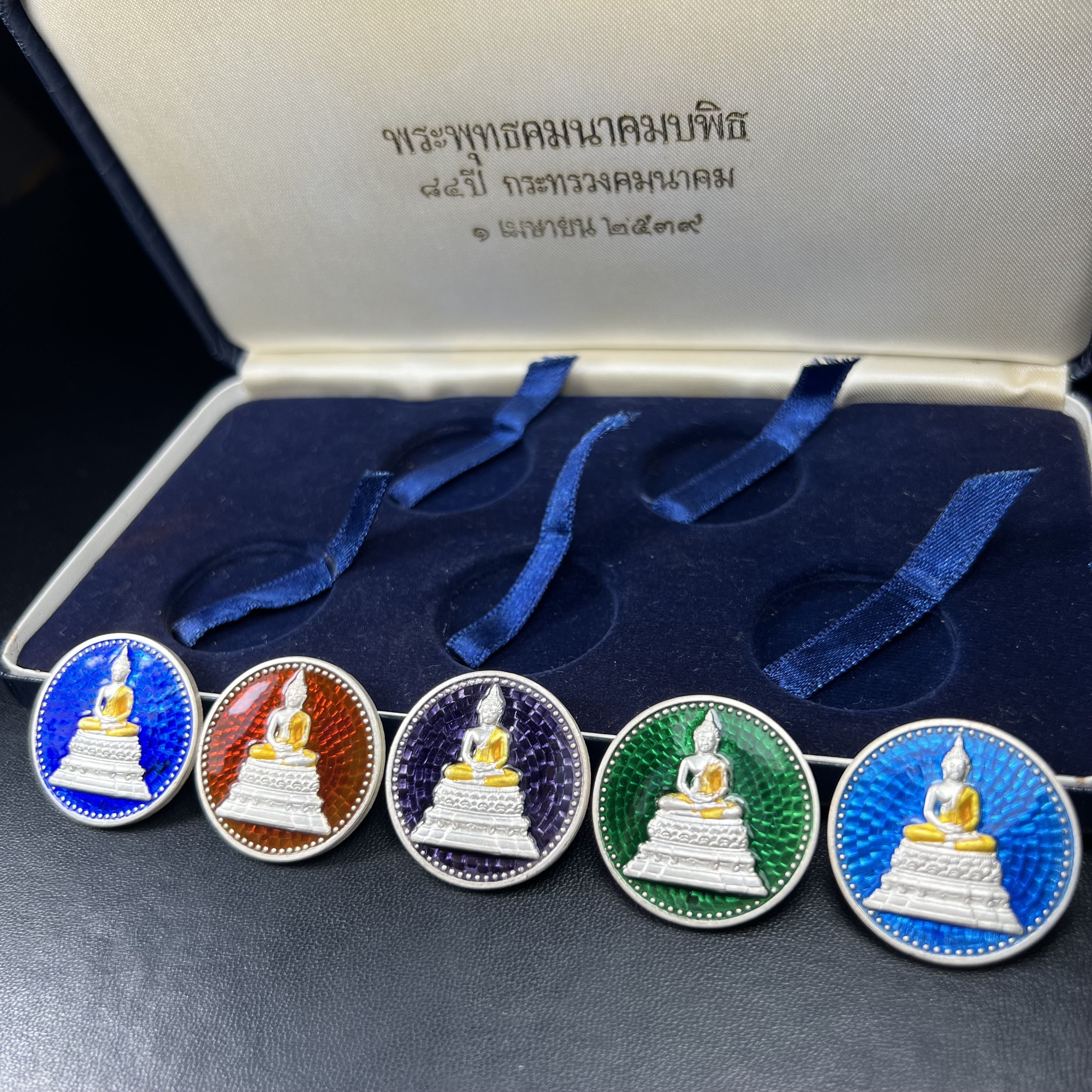 พระพุทธคมนาคมบพิธ (พระพุทธสิหิงค์จำลอง)(พระพุทธรูปประจำกระทรวงคมนาคม) หลังตรา ภปร. ครบรอบ 84 ปี กระทรวงคมนาคม พ.ศ.2539 ชุดเหรียญเนื้อเงินลงยา ขนาด 2.8 ซม. ครบชุดห้าสีพร้อมกล่องบรรจุเดิม ปลุกเสก ณ วัดพระแก้ว พิธีใหญ่