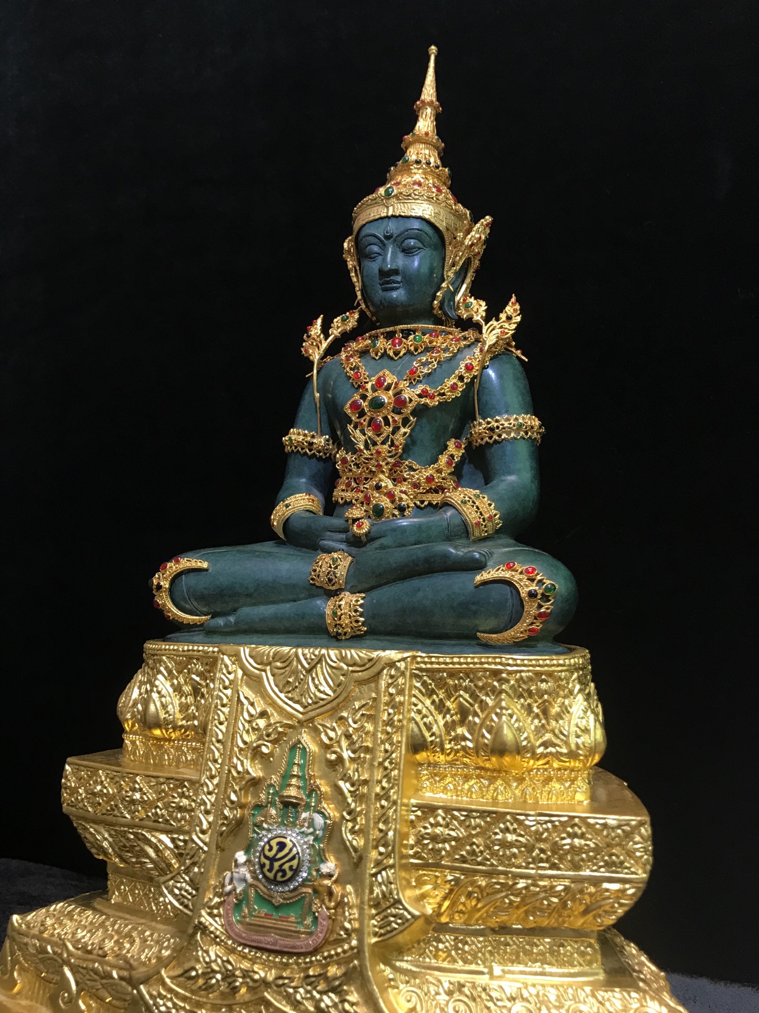 พระแก้วมรกต(จำลอง)ลอยองค์ ขนาดหน้าตัก 5 นิ้ว ทรงเครื่องฤดูร้อน เนื้อโลหะเคลือบสีเขียว เครื่องทรงชุบทองลงยาสี ฐานเนื้อโลหะ ลงรักปิดทองคำ ประดิษฐานตราสัญลักษณ์ฉลองสิริราชสมบัติ ครบ 60 ปี