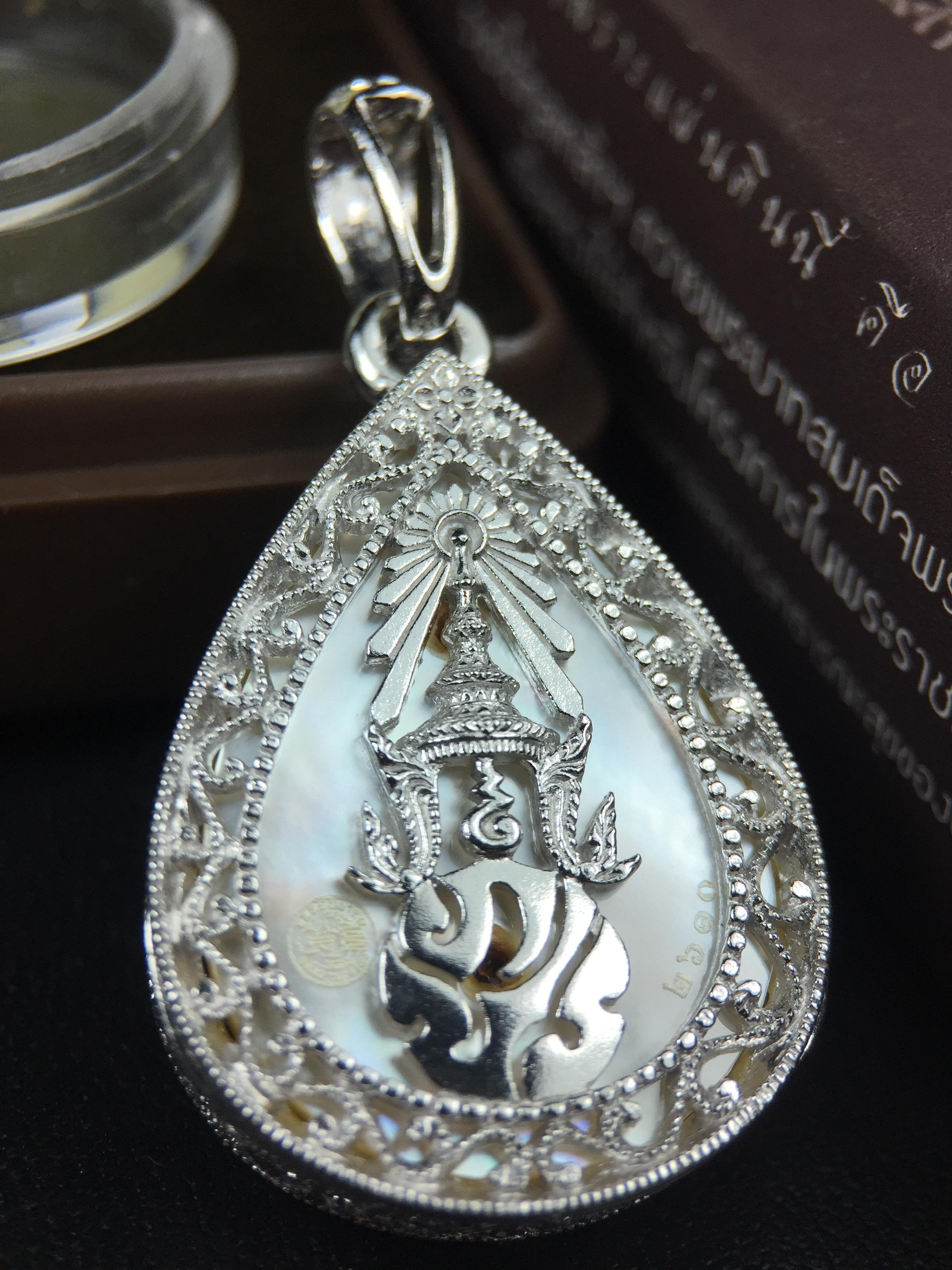 พระพุทธชินราช ภปร. โครงการ "เพราะแผ่นดินนี้ คือ แผ่นดินเกิด" ปี2548(รุ่นแรก) เหรียญทรงหยดน้ำ ขนาด 21 x 31 มม. เนื้อเงินสามกษัตริย์ องค์พระชุบสามกษัตริย์ ล้อมด้วยกรอบเงินชุบทองคำขาวสลักเสลาเป็นลวดลายละเอียดอ่อน ส่วนพื้นองค์พระเป็นเปลือกหอยมุข