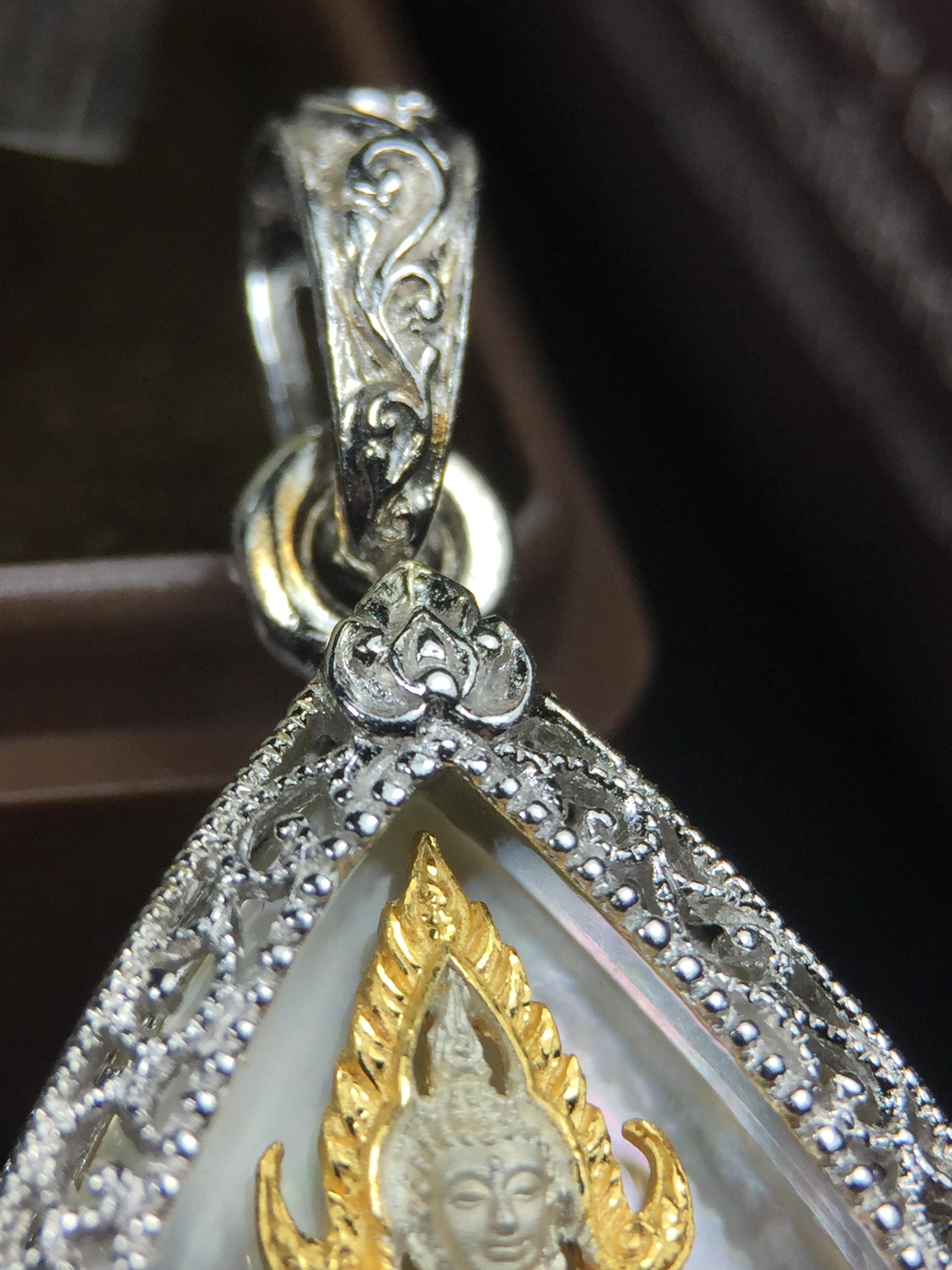 พระพุทธชินราช ภปร. โครงการ "เพราะแผ่นดินนี้ คือ แผ่นดินเกิด" ปี2548(รุ่นแรก) เหรียญทรงหยดน้ำ ขนาด 21 x 31 มม. เนื้อเงินสามกษัตริย์ องค์พระชุบสามกษัตริย์ ล้อมด้วยกรอบเงินชุบทองคำขาวสลักเสลาเป็นลวดลายละเอียดอ่อน ส่วนพื้นองค์พระเป็นเปลือกหอยมุข