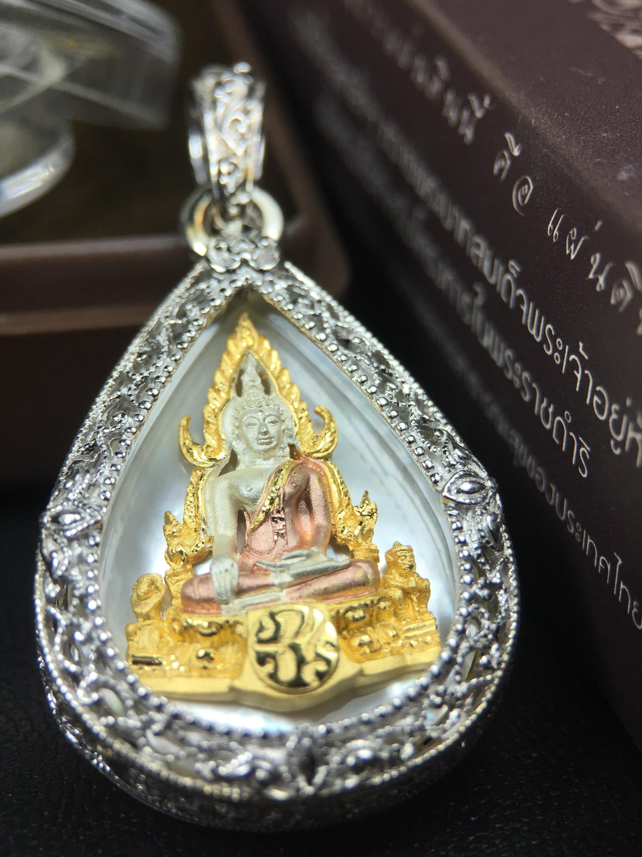 พระพุทธชินราช ภปร. โครงการ "เพราะแผ่นดินนี้ คือ แผ่นดินเกิด" ปี2548(รุ่นแรก) เหรียญทรงหยดน้ำ ขนาด 21 x 31 มม. เนื้อเงินสามกษัตริย์ องค์พระชุบสามกษัตริย์ ล้อมด้วยกรอบเงินชุบทองคำขาวสลักเสลาเป็นลวดลายละเอียดอ่อน ส่วนพื้นองค์พระเป็นเปลือกหอยมุข