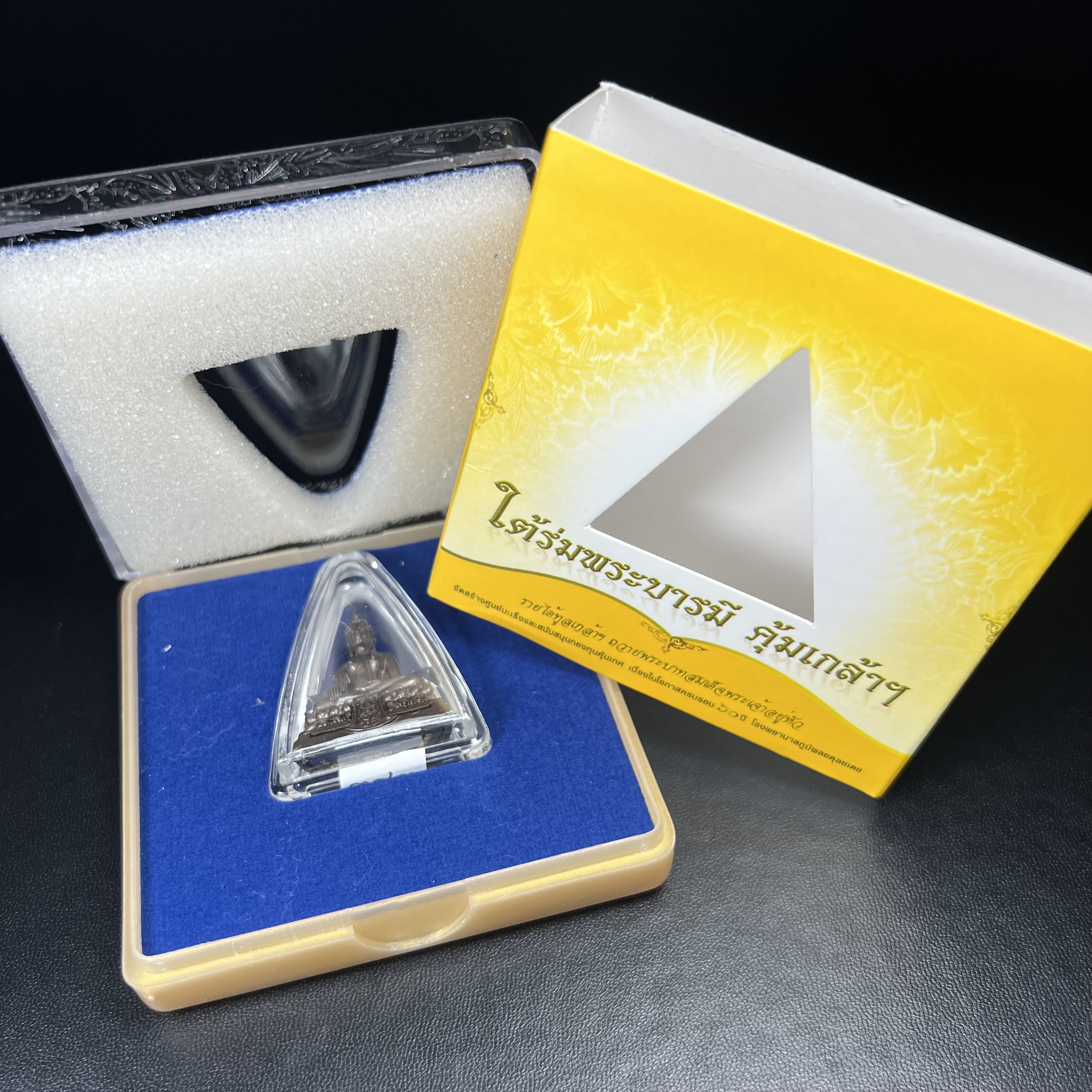 พระพุทธรูปคุ้มเกล้าฯ ภปร.(ใต้ร่มพระบารมี คุ้มเกล้า) 60ปี โรงพยาบาลภูมิพลฯ พ.ศ.2552 เนื้อนวโลหะ รมดำ(พิมพ์ใหญ่ขนาด 35.5*24 มม.)สภาพสวยเดิมพร้อมกล่องบรรจุเดิม ตอกโค๊ดหมายเลขกำกับ