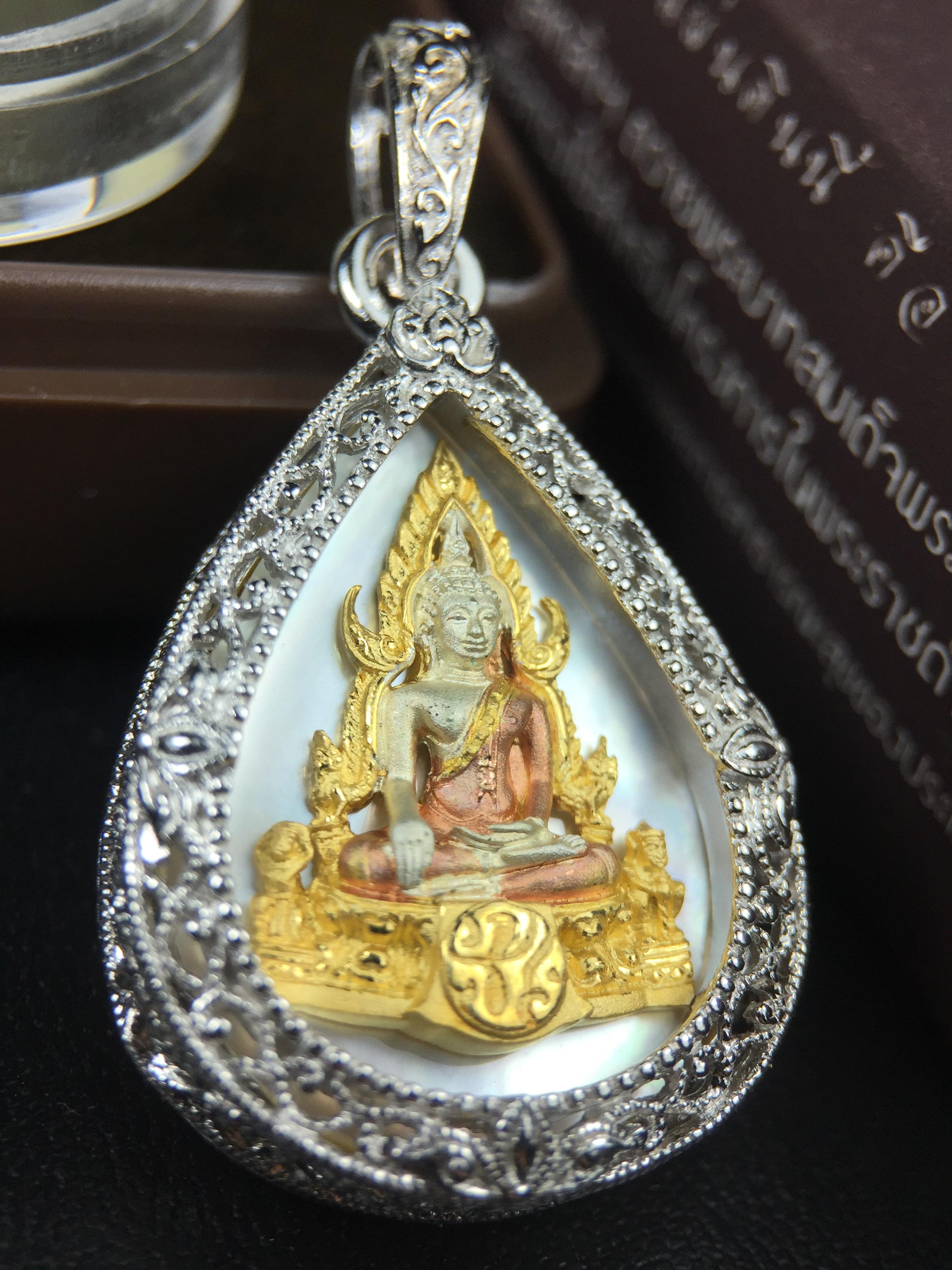 พระพุทธชินราช ภปร. โครงการ "เพราะแผ่นดินนี้ คือ แผ่นดินเกิด" ปี2548(รุ่นแรก) เหรียญทรงหยดน้ำ ขนาด 21 x 31 มม. เนื้อเงินสามกษัตริย์ องค์พระชุบสามกษัตริย์ ล้อมด้วยกรอบเงินชุบทองคำขาวสลักเสลาเป็นลวดลายละเอียดอ่อน ส่วนพื้นองค์พระเป็นเปลือกหอยมุข