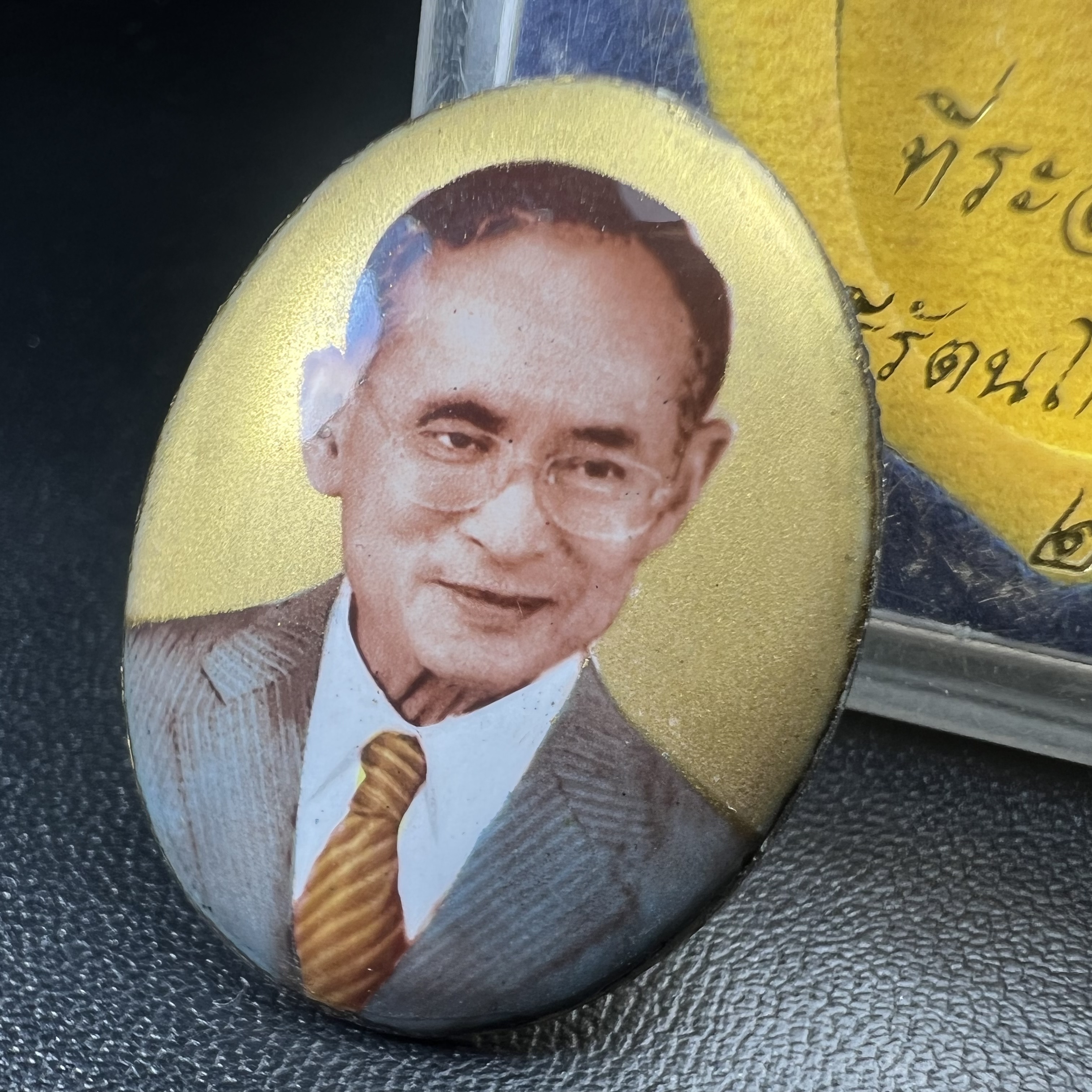 ล็อกเกตในหลวงรัชกาลที่9 ที่ระลึกครบ 25 ปี มูลนิธิศรีรัตนโกสินทร์ วัดสุทธาราม พ.ศ. 2550 พิมพ์ทรงวงรีรูปไข่เล็กฉากสีทอง หลังปิดแผ่นโลหะสีขาว(สแตนเลส)ฝังพระยอดธง(นิยม)