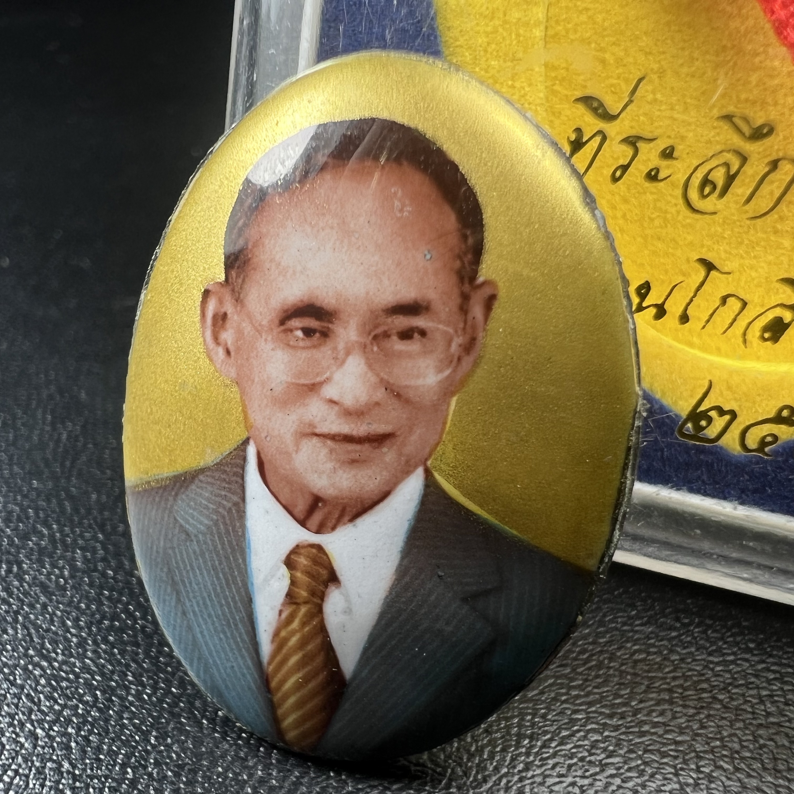 ล็อกเกตในหลวงรัชกาลที่9 ที่ระลึกครบ 25 ปี มูลนิธิศรีรัตนโกสินทร์ วัดสุทธาราม พ.ศ. 2550 พิมพ์ทรงวงรีรูปไข่เล็กฉากสีทอง หลังปิดแผ่นโลหะสีขาว(สแตนเลส)ฝังพระยอดธง(นิยม)