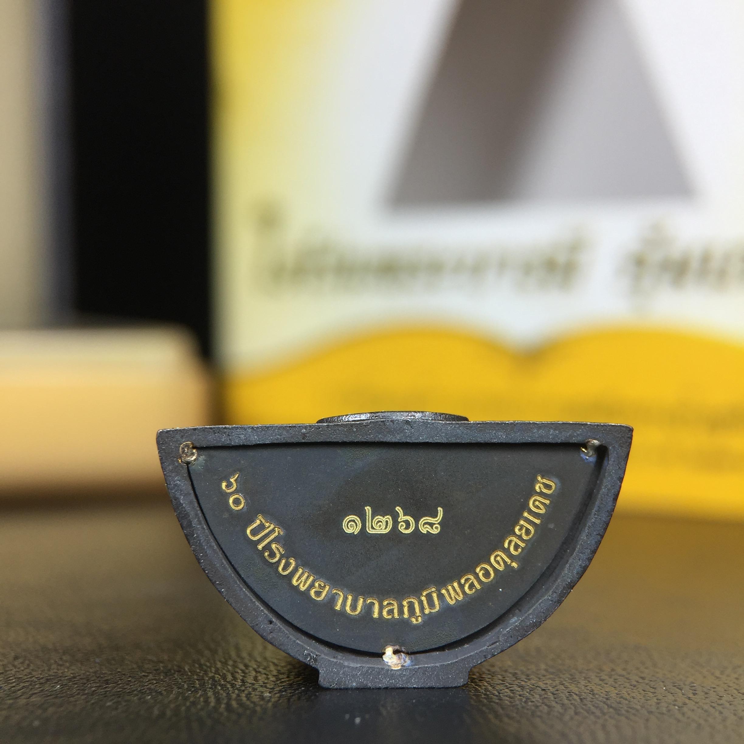 พระพุทธรูปคุ้มเกล้าฯ ภปร.(ใต้ร่มพระบารมี คุ้มเกล้า) 60ปี โรงพยาบาลภูมิพลฯ พ.ศ.2552 เนื้อนวโลหะ รมดำ(พิมพ์ใหญ่ขนาด 35.5*24 มม.)สภาพสวยเดิมพร้อมกล่องบรรจุเดิม ตอกโค๊ดหมายเลขกำกับ