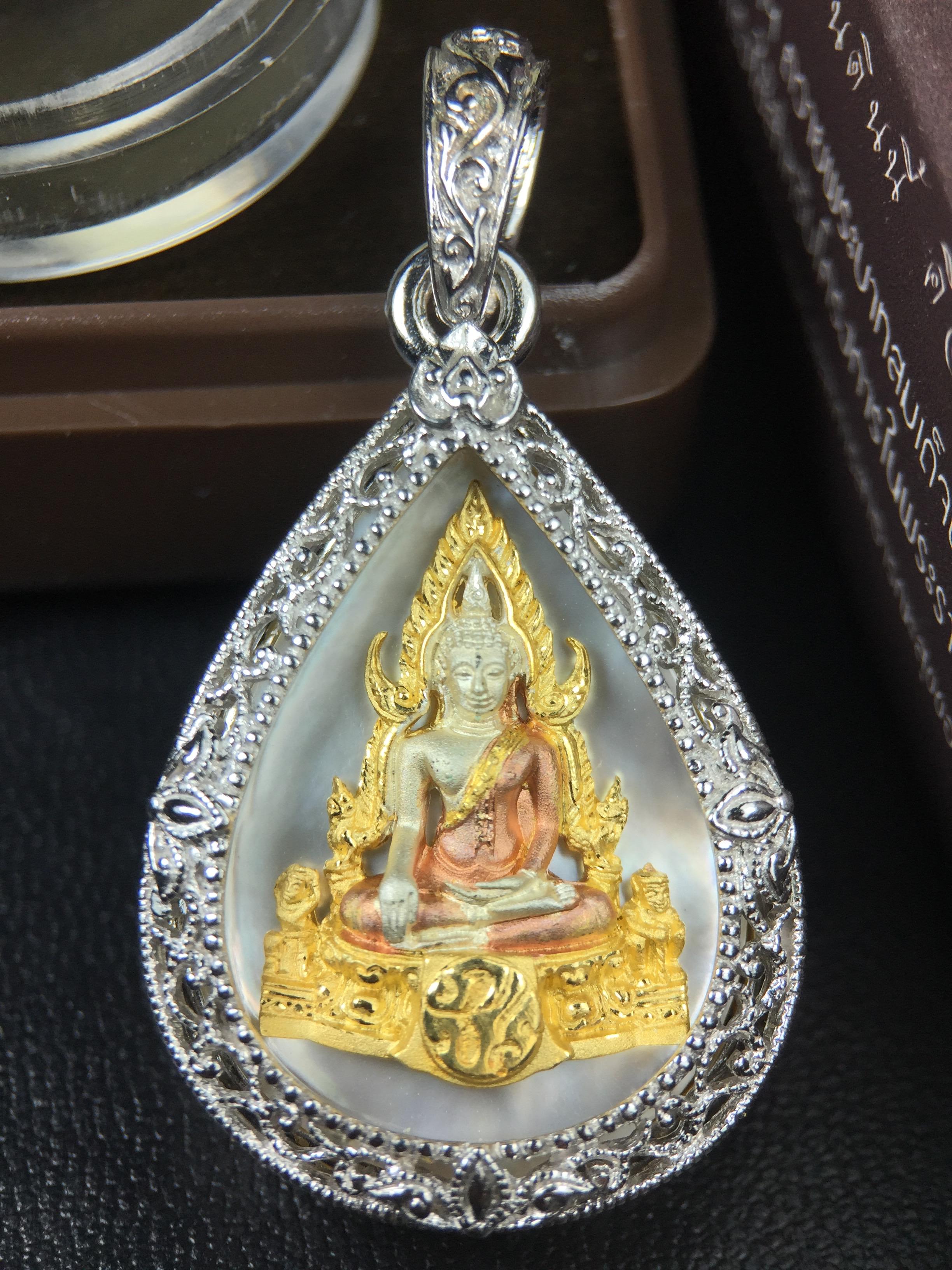 พระพุทธชินราช ภปร. โครงการ "เพราะแผ่นดินนี้ คือ แผ่นดินเกิด" ปี2548(รุ่นแรก) เหรียญทรงหยดน้ำ ขนาด 21 x 31 มม. เนื้อเงินสามกษัตริย์ องค์พระชุบสามกษัตริย์ ล้อมด้วยกรอบเงินชุบทองคำขาวสลักเสลาเป็นลวดลายละเอียดอ่อน ส่วนพื้นองค์พระเป็นเปลือกหอยมุข