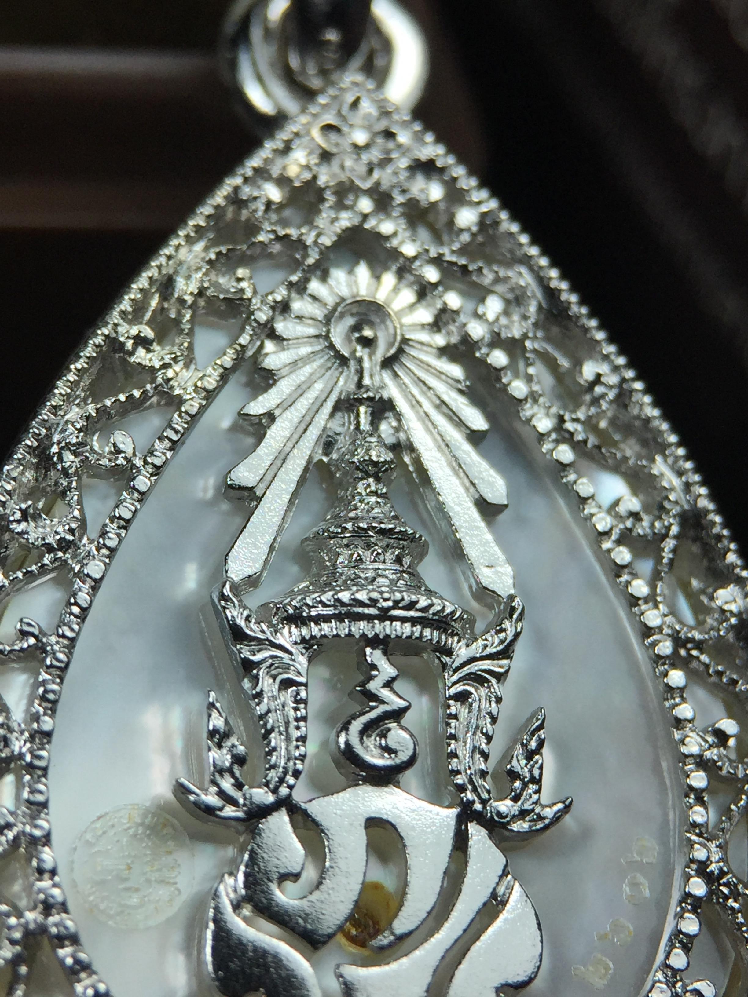 พระพุทธชินราช ภปร. โครงการ "เพราะแผ่นดินนี้ คือ แผ่นดินเกิด" ปี2548(รุ่นแรก) เหรียญทรงหยดน้ำ ขนาด 21 x 31 มม. เนื้อเงินสามกษัตริย์ องค์พระชุบสามกษัตริย์ ล้อมด้วยกรอบเงินชุบทองคำขาวสลักเสลาเป็นลวดลายละเอียดอ่อน ส่วนพื้นองค์พระเป็นเปลือกหอยมุข