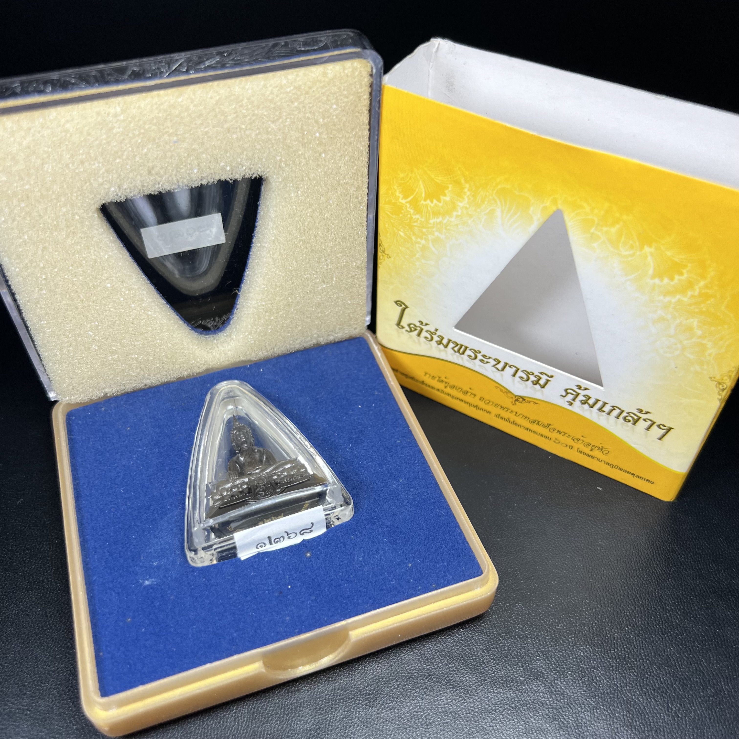 พระพุทธรูปคุ้มเกล้าฯ ภปร.(ใต้ร่มพระบารมี คุ้มเกล้า) 60ปี โรงพยาบาลภูมิพลฯ พ.ศ.2552 เนื้อนวโลหะ รมดำ(พิมพ์ใหญ่ขนาด 35.5*24 มม.)สภาพสวยเดิมพร้อมกล่องบรรจุเดิม ตอกโค๊ดหมายเลขกำกับ