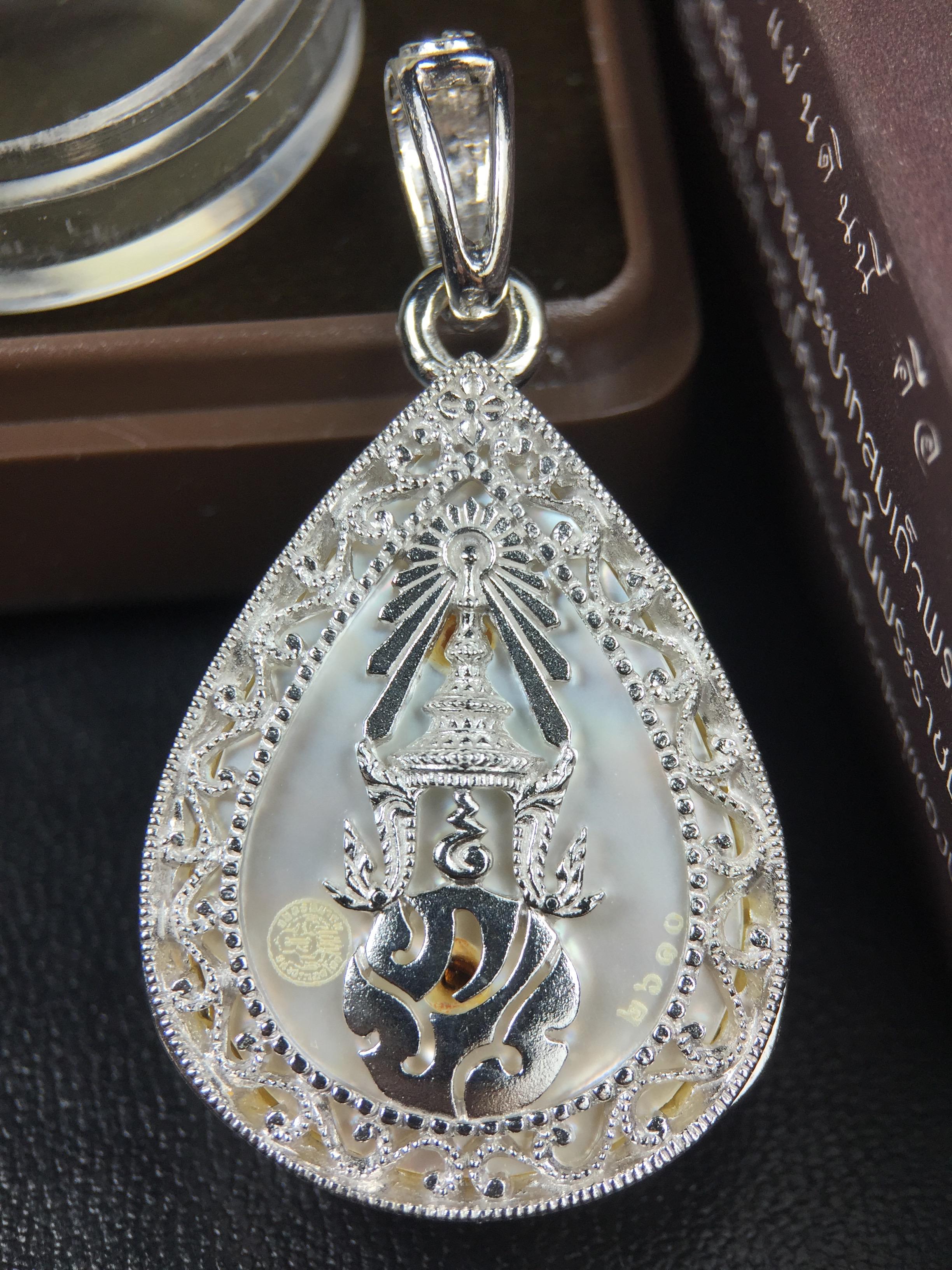 พระพุทธชินราช ภปร. โครงการ "เพราะแผ่นดินนี้ คือ แผ่นดินเกิด" ปี2548(รุ่นแรก) เหรียญทรงหยดน้ำ ขนาด 21 x 31 มม. เนื้อเงินสามกษัตริย์ องค์พระชุบสามกษัตริย์ ล้อมด้วยกรอบเงินชุบทองคำขาวสลักเสลาเป็นลวดลายละเอียดอ่อน ส่วนพื้นองค์พระเป็นเปลือกหอยมุข