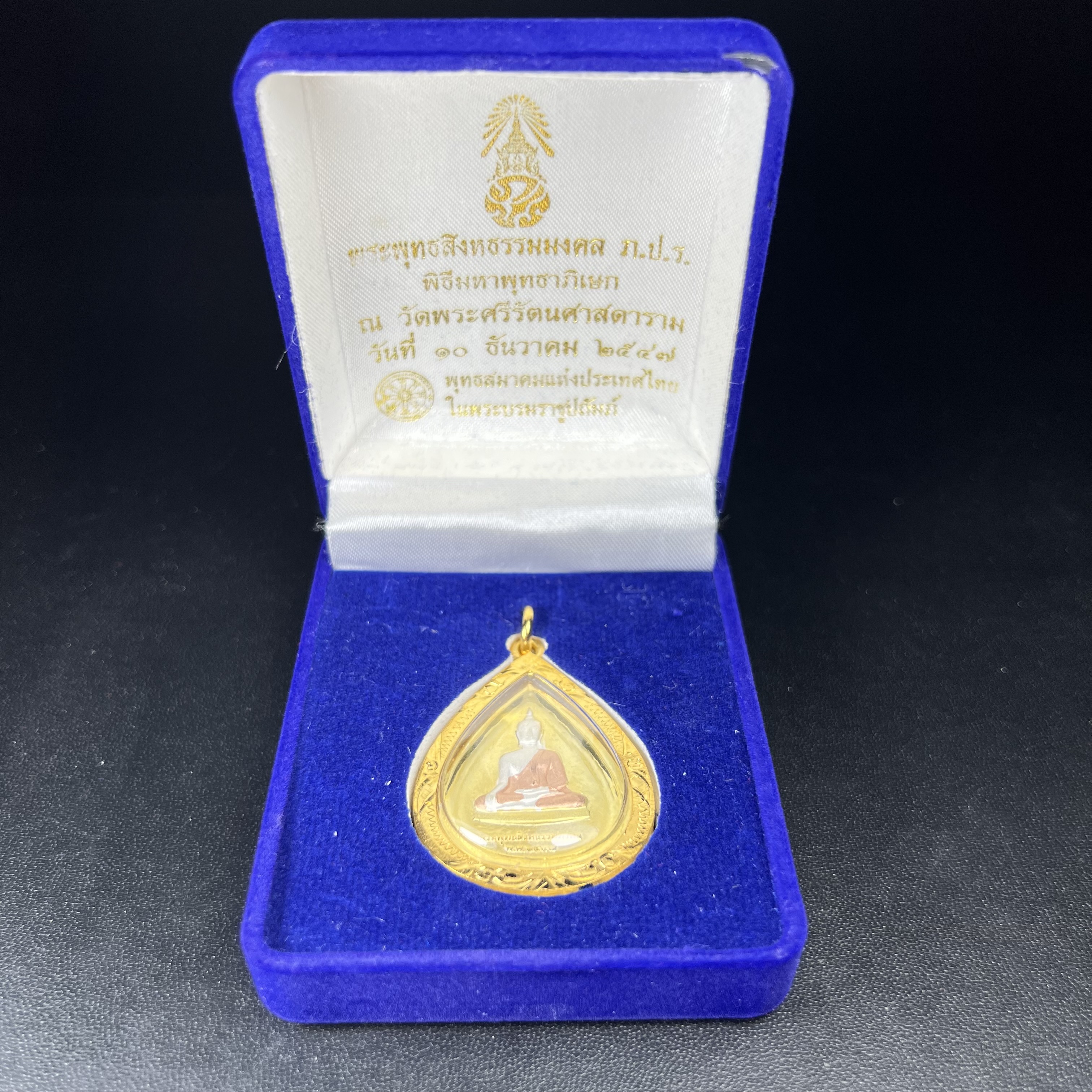 เหรียญพระพุทธสิงหธรรมมงคล ภปร. ปี 2547 ทรงหยดน้ำ ด้านหลังมี ภ.ป.ร. (ชนวนเก่า)เนื้อโลหะผสม ชุบทองสามกษัตริย์ สูง 3.3ซม.พิธีใหญ่ มวลสารดี ปลุกเสกวัดพระแก้ว(งานเลี่ยมกรอบเดิมจากผู้จัดสร้างห่อหุ้มด้วยทองนพเกล้า)