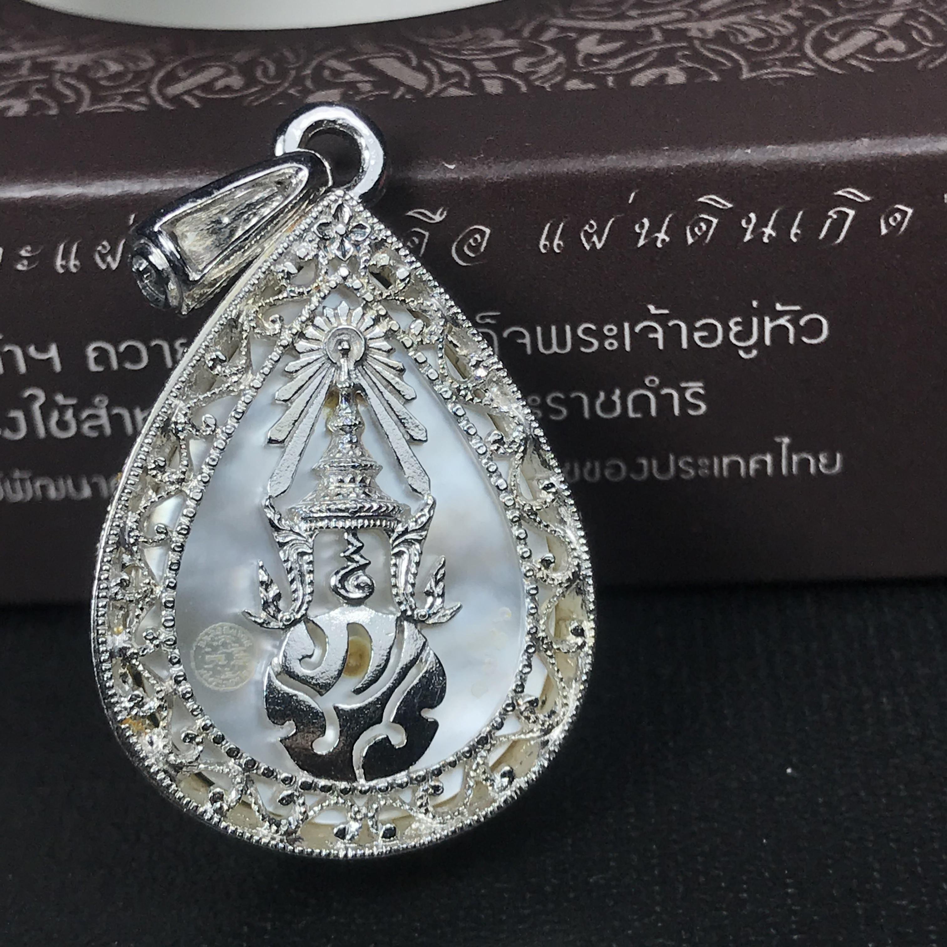 พระพุทธชินราช ภปร. โครงการ "เพราะแผ่นดินนี้ คือ แผ่นดินเกิด" ปี2548(รุ่นแรก) เหรียญทรงหยดน้ำ ขนาด 21 x 31 มม. เนื้อเงินสามกษัตริย์ องค์พระชุบสามกษัตริย์ ล้อมด้วยกรอบเงินชุบทองคำขาวสลักเสลาเป็นลวดลายละเอียดอ่อน ส่วนพื้นองค์พระเป็นเปลือกหอยมุข