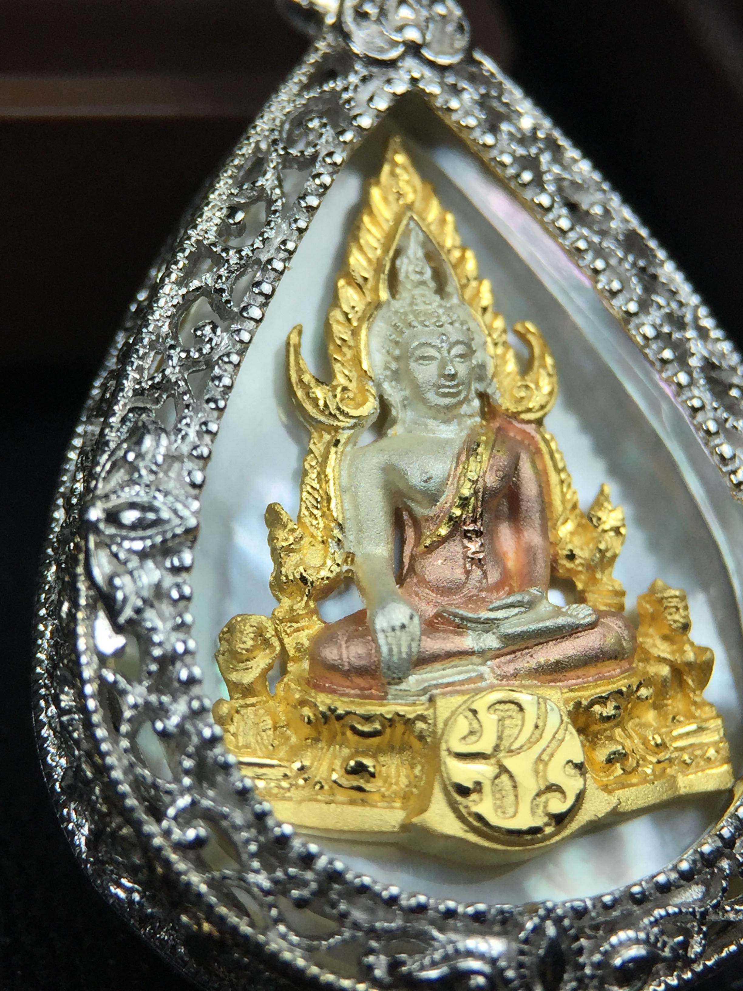 พระพุทธชินราช ภปร. โครงการ "เพราะแผ่นดินนี้ คือ แผ่นดินเกิด" ปี2548(รุ่นแรก) เหรียญทรงหยดน้ำ ขนาด 21 x 31 มม. เนื้อเงินสามกษัตริย์ องค์พระชุบสามกษัตริย์ ล้อมด้วยกรอบเงินชุบทองคำขาวสลักเสลาเป็นลวดลายละเอียดอ่อน ส่วนพื้นองค์พระเป็นเปลือกหอยมุข