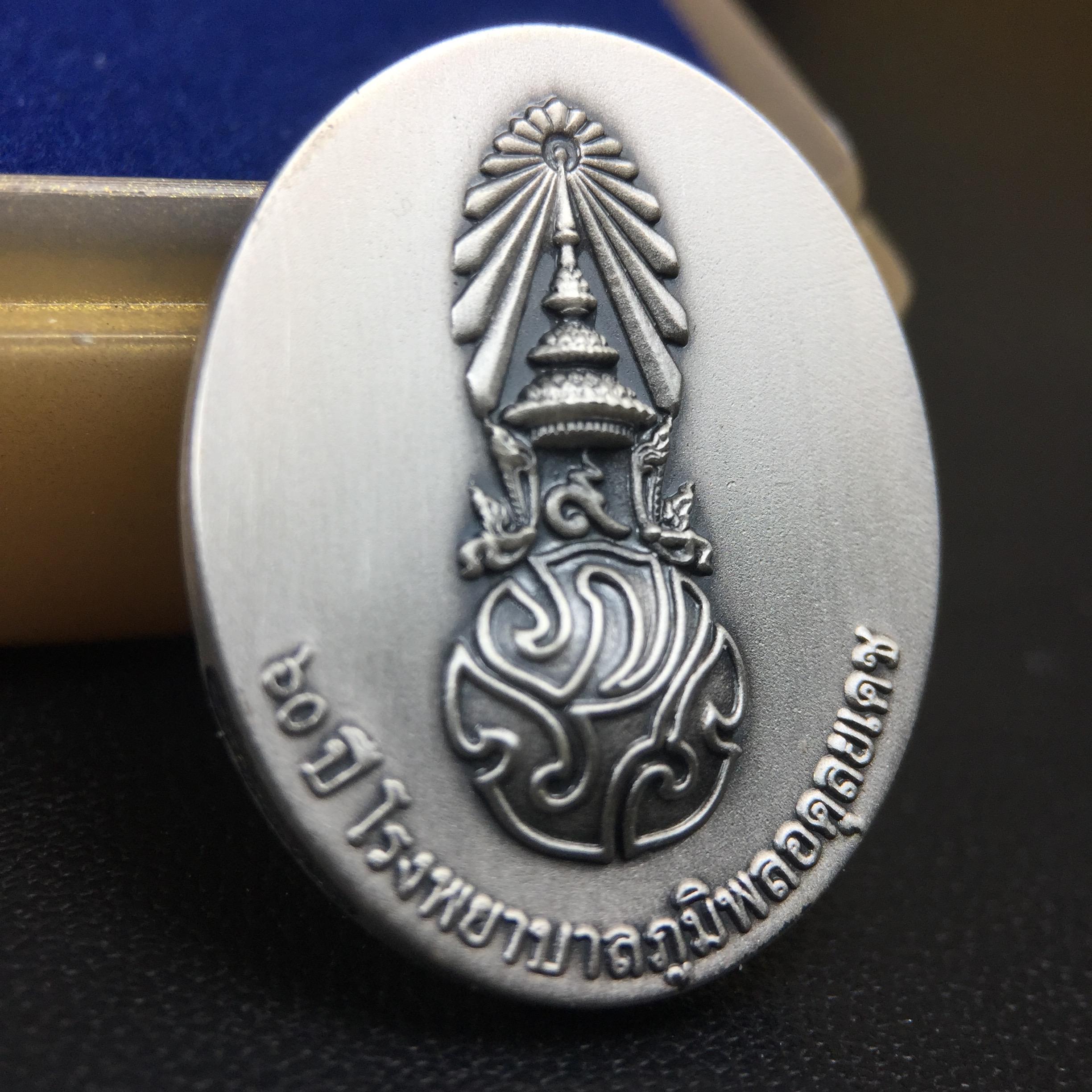 เหรียญพระบาทสมเด็จพระเจ้าอยู่หัวรัชกาลที่ 9 ภปร.(ใต้ร่มพระบารมี คุ้มเกล้า) 60ปี โรงพยาบาลภูมิพลฯ พ.ศ.2552 เนื้อเงิน (พิมพ์เล็กขนาด 25*20 มม.)สภาพสวยเดิมพร้อมกล่องบรรจุเดิม ตอกโค๊ดหมายเลขกำกับ เนื้อเงินหายากพบเจอน้อย