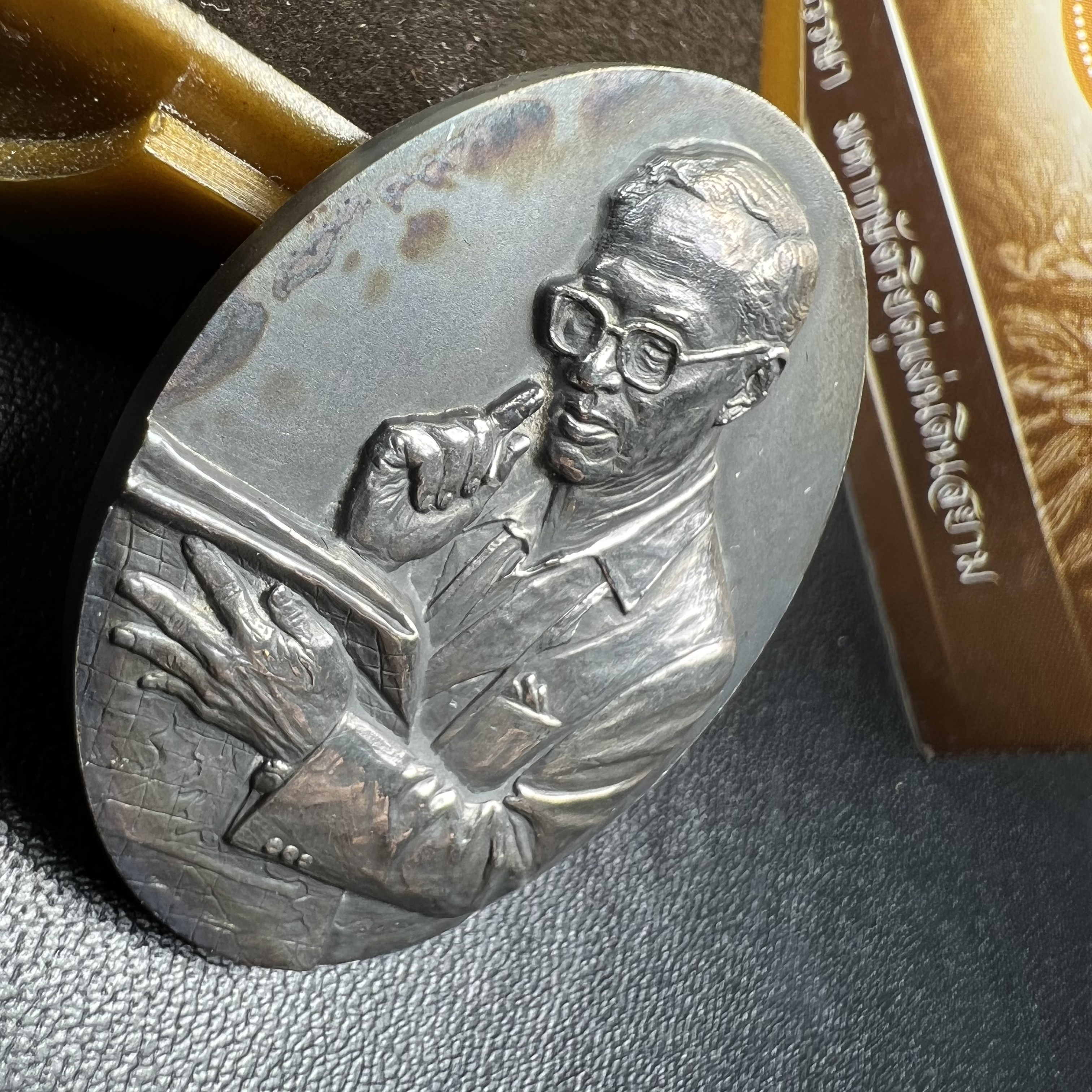 เหรียญรูปหล่อพระบาทสมเด็จพระเจ้าอยู่หัว ในหลวงทรงงาน “รุ่นเย็นศิระเพราะพระบริบาล 80พรรษา มหากษัตริย์คู่แผ่นดินสยาม” พ.ศ.2550 เนื้อเงินรมดำ(ขนาด 27*35 มม.) พร้อมกล่องบรรจุเดิมครบ