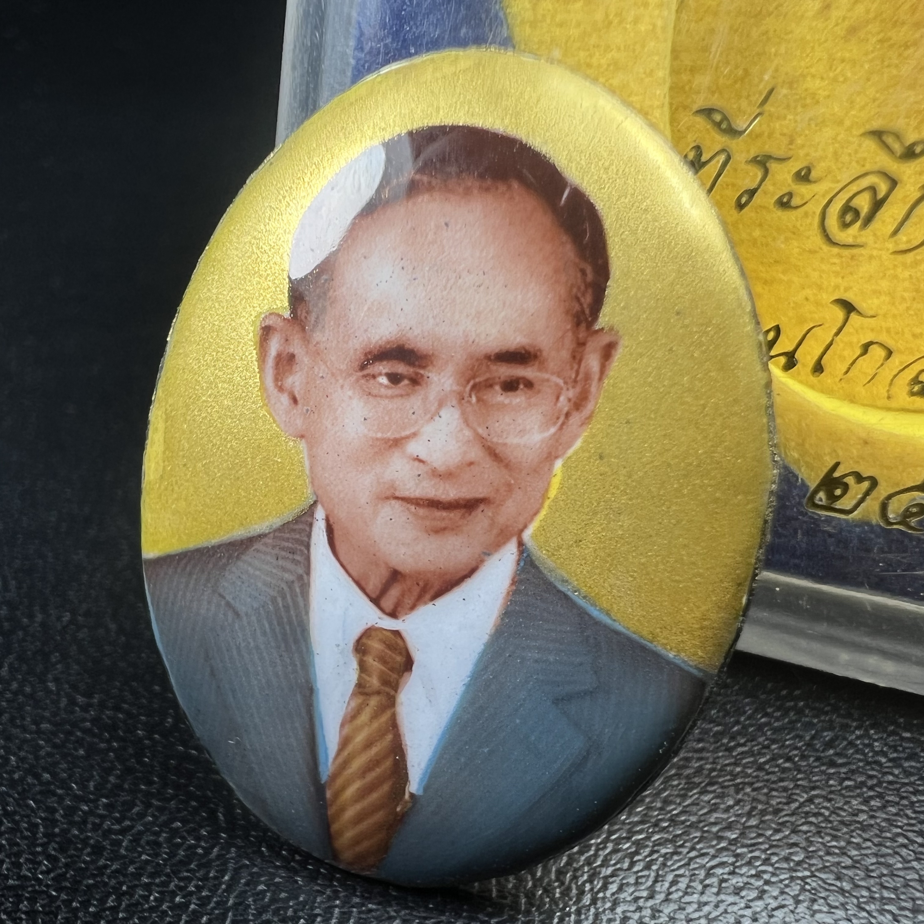 ล็อกเกตในหลวงรัชกาลที่9 ที่ระลึกครบ 25 ปี มูลนิธิศรีรัตนโกสินทร์ วัดสุทธาราม พ.ศ. 2550 พิมพ์ทรงวงรีรูปไข่เล็กฉากสีทอง หลังปิดแผ่นโลหะสีขาว(สแตนเลส)ฝังพระยอดธง(นิยม)