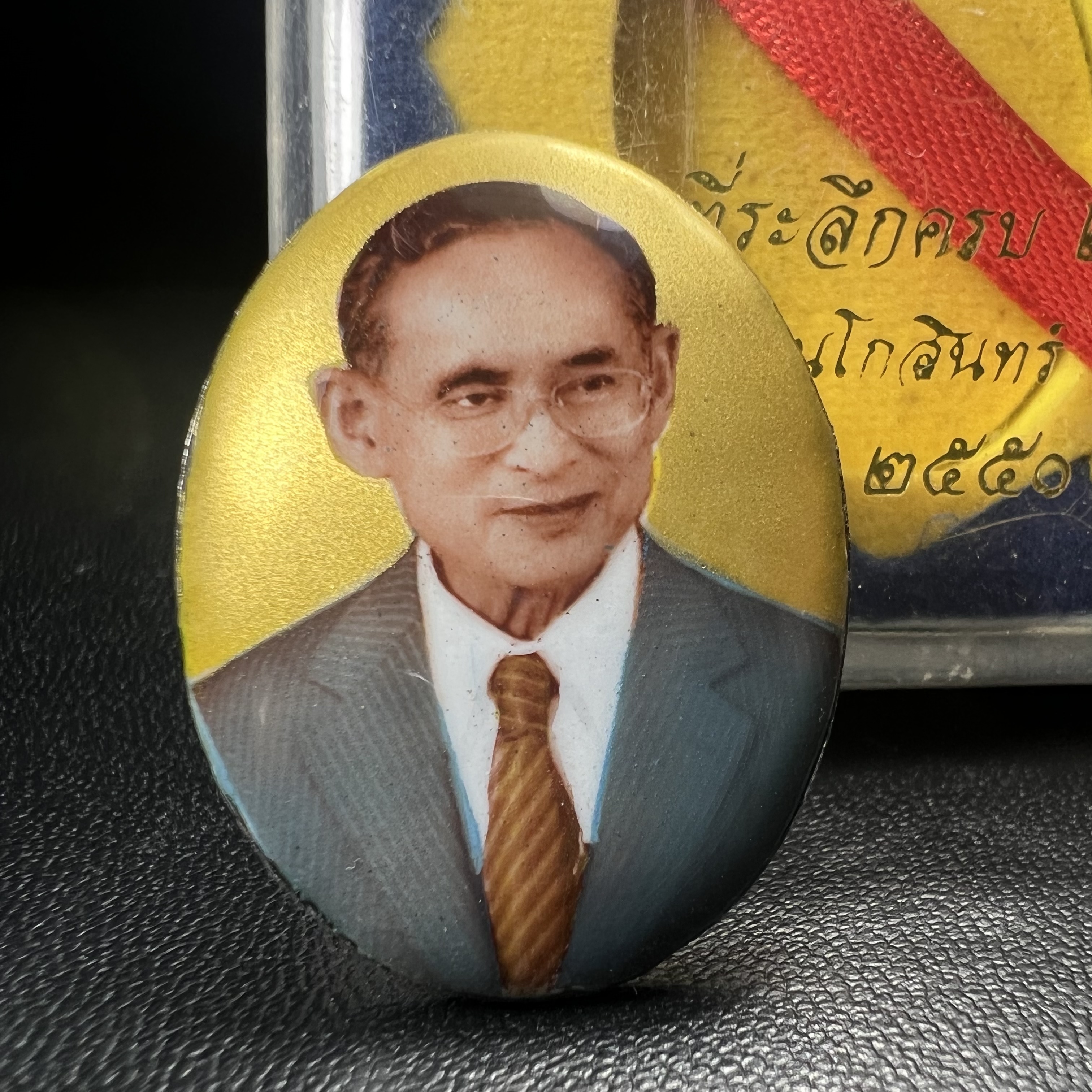 ล็อกเกตในหลวงรัชกาลที่9 ที่ระลึกครบ 25 ปี มูลนิธิศรีรัตนโกสินทร์ วัดสุทธาราม พ.ศ. 2550 พิมพ์ทรงวงรีรูปไข่เล็กฉากสีทอง หลังปิดแผ่นโลหะสีขาว(สแตนเลส)ฝังพระยอดธง(นิยม)