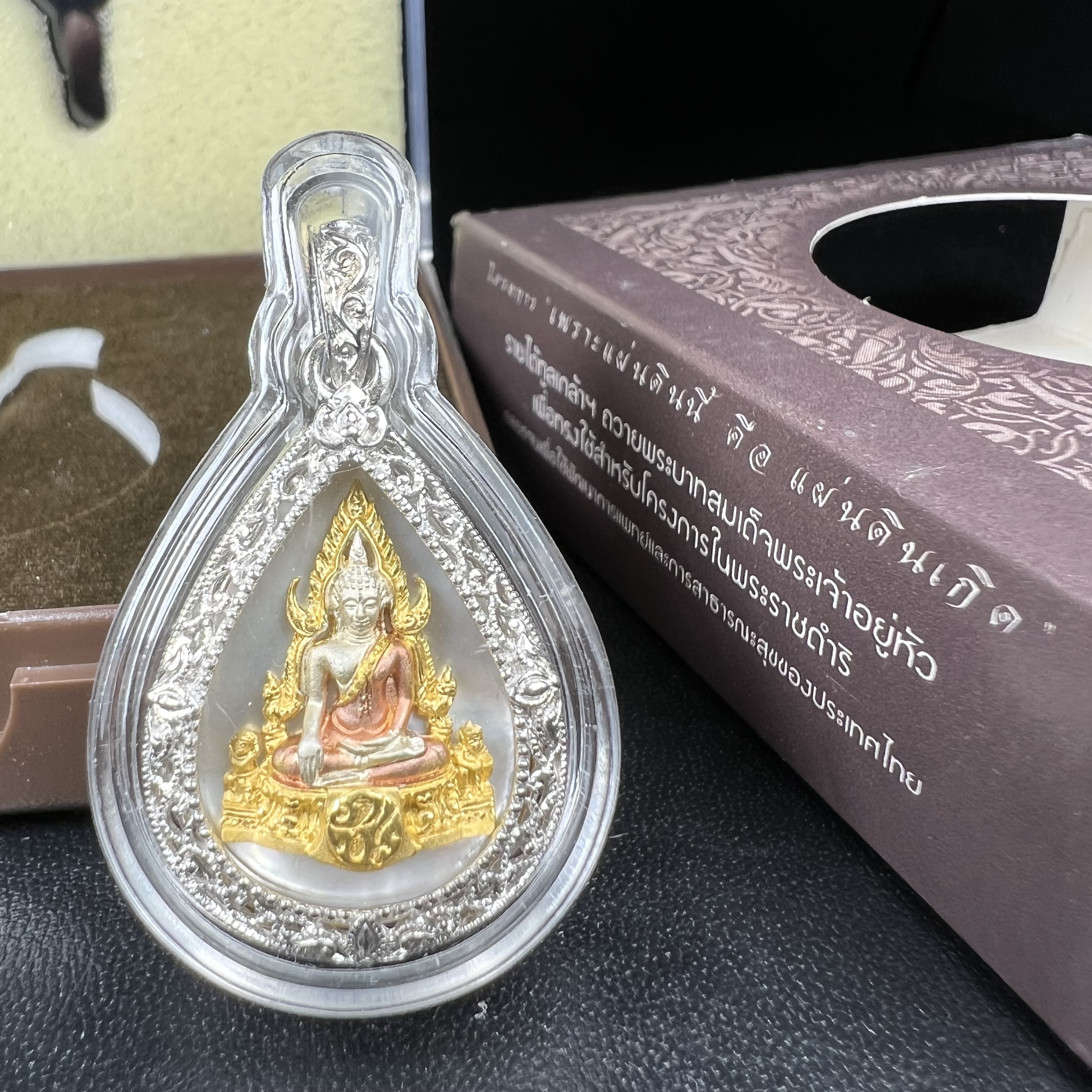 พระพุทธชินราช ภปร. โครงการ "เพราะแผ่นดินนี้ คือ แผ่นดินเกิด" ปี2548(รุ่นแรก) เหรียญทรงหยดน้ำ ขนาด 21 x 31 มม. เนื้อเงินสามกษัตริย์ องค์พระชุบสามกษัตริย์ ล้อมด้วยกรอบเงินชุบทองคำขาวสลักเสลาเป็นลวดลายละเอียดอ่อน ส่วนพื้นองค์พระเป็นเปลือกหอยมุข