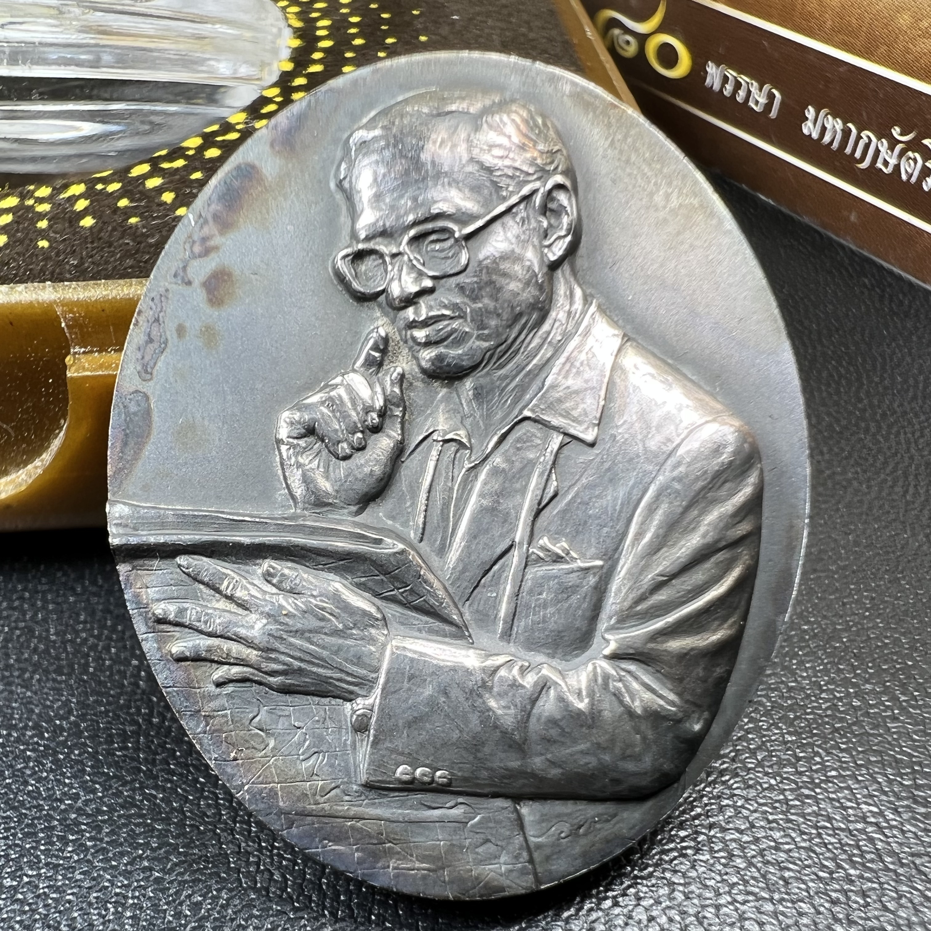 เหรียญรูปหล่อพระบาทสมเด็จพระเจ้าอยู่หัว ในหลวงทรงงาน “รุ่นเย็นศิระเพราะพระบริบาล 80พรรษา มหากษัตริย์คู่แผ่นดินสยาม” พ.ศ.2550 เนื้อเงินรมดำ(ขนาด 27*35 มม.) พร้อมกล่องบรรจุเดิมครบ