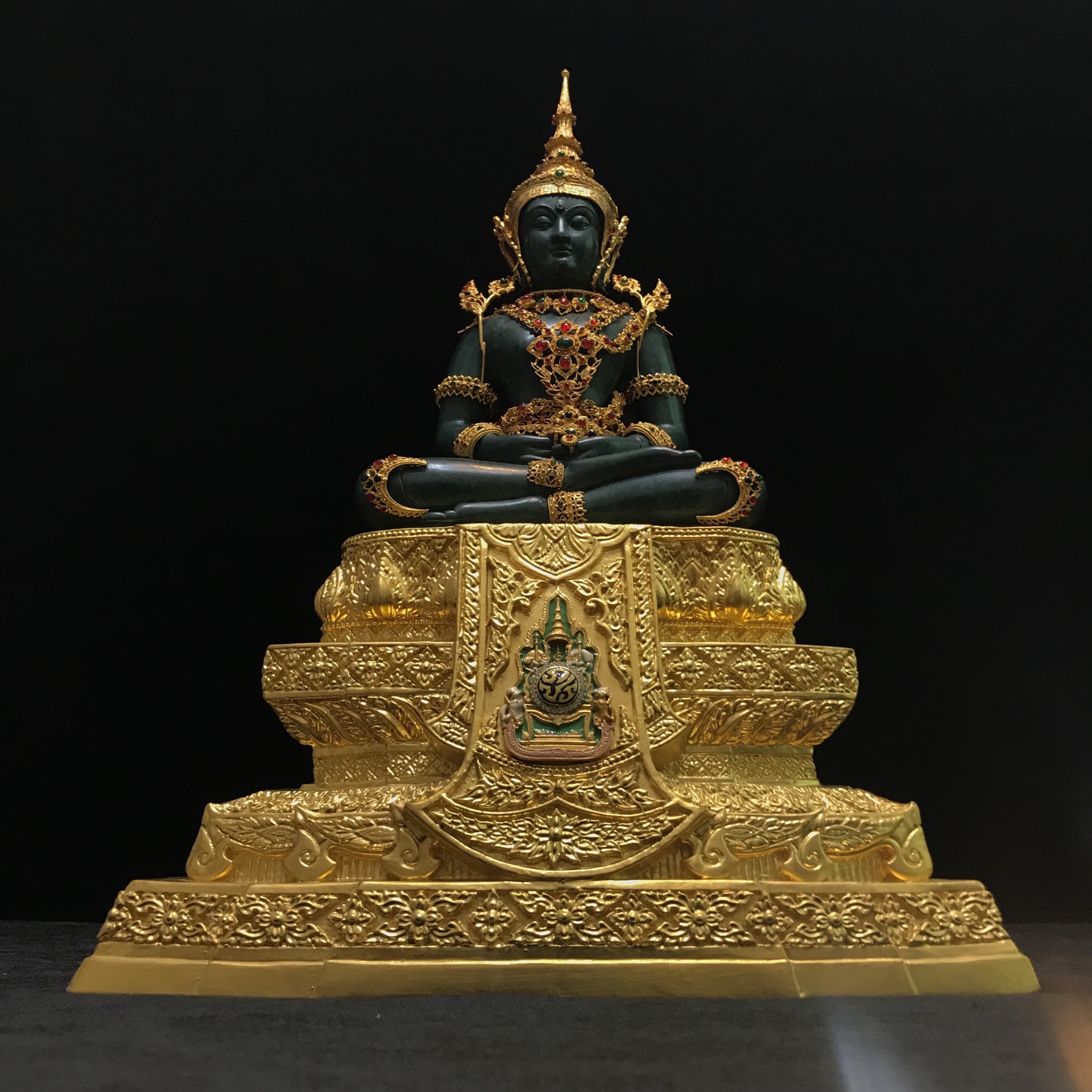 พระแก้วมรกต(จำลอง)ลอยองค์ ขนาดหน้าตัก 5 นิ้ว ทรงเครื่องฤดูร้อน เนื้อโลหะเคลือบสีเขียว เครื่องทรงชุบทองลงยาสี ฐานเนื้อโลหะ ลงรักปิดทองคำ ประดิษฐานตราสัญลักษณ์ฉลองสิริราชสมบัติ ครบ 60 ปี