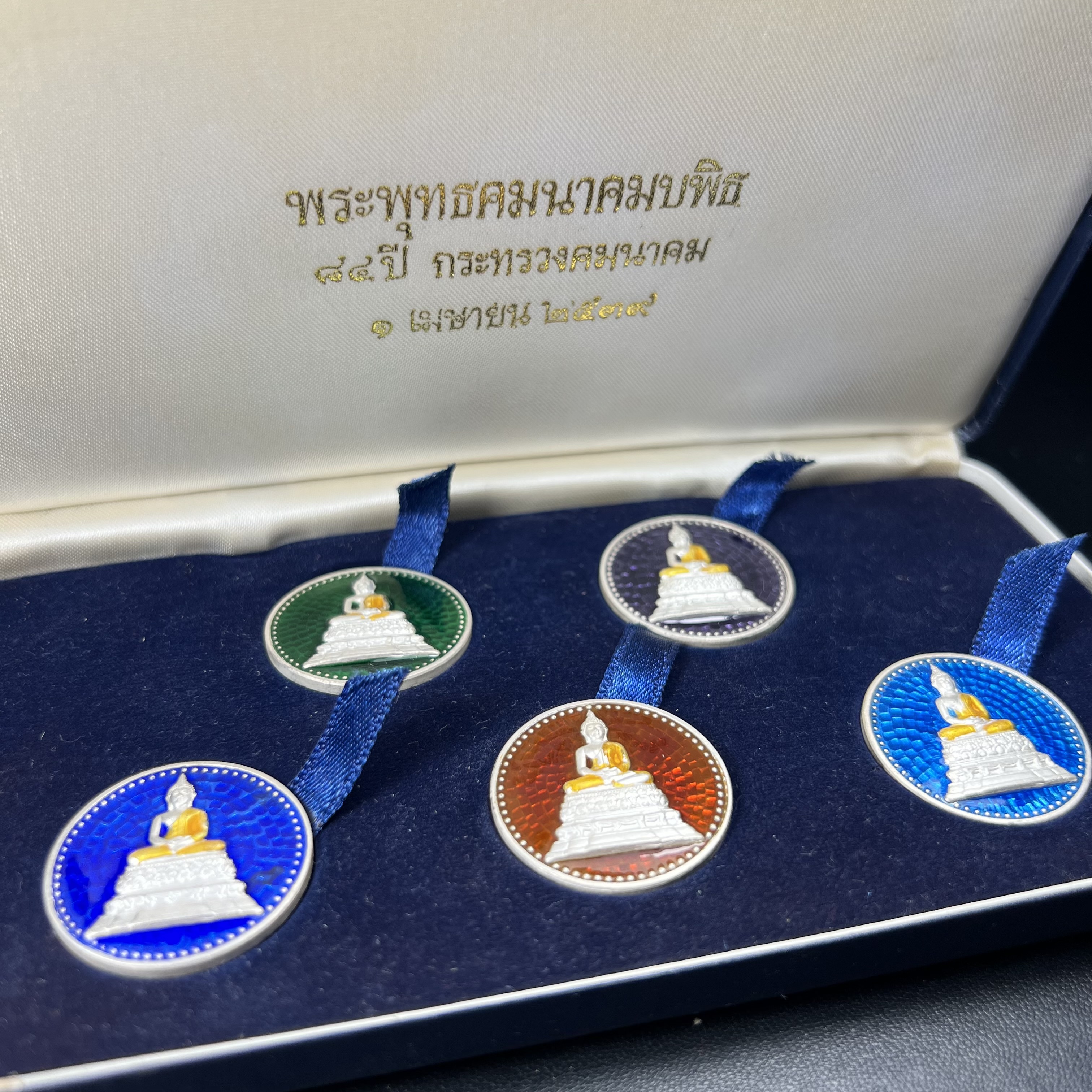 พระพุทธคมนาคมบพิธ (พระพุทธสิหิงค์จำลอง)(พระพุทธรูปประจำกระทรวงคมนาคม) หลังตรา ภปร. ครบรอบ 84 ปี กระทรวงคมนาคม พ.ศ.2539 ชุดเหรียญเนื้อเงินลงยา ขนาด 2.8 ซม. ครบชุดห้าสีพร้อมกล่องบรรจุเดิม ปลุกเสก ณ วัดพระแก้ว พิธีใหญ่