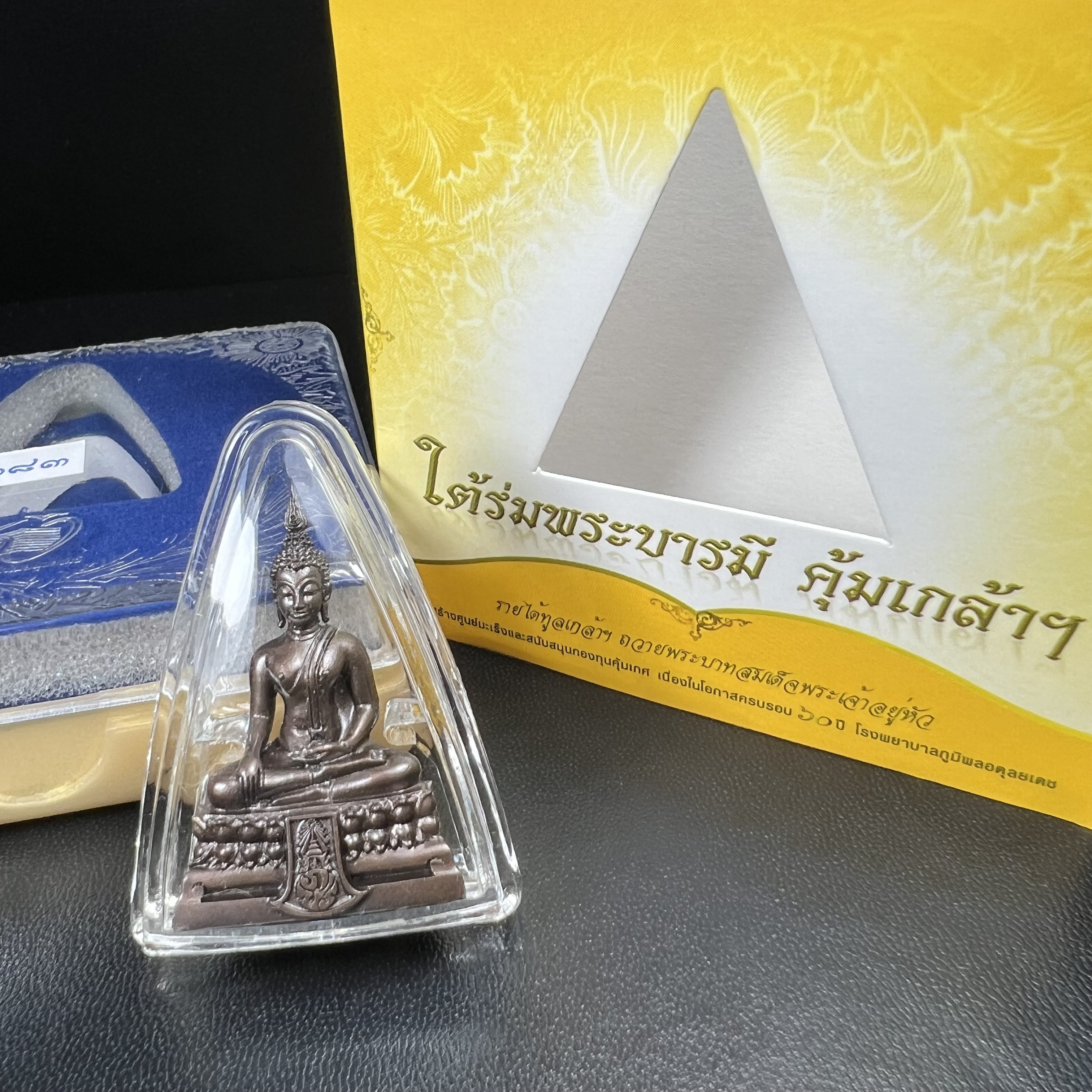 พระพุทธรูปคุ้มเกล้าฯ ภปร.(ใต้ร่มพระบารมี คุ้มเกล้า) 60ปี โรงพยาบาลภูมิพลฯ พ.ศ.2552 เนื้อนวโลหะ รมดำ(พิมพ์ใหญ่ขนาด 35.5*24 มม.)สภาพสวยเดิมพร้อมกล่องบรรจุเดิม ตอกโค๊ดหมายเลขกำกับ