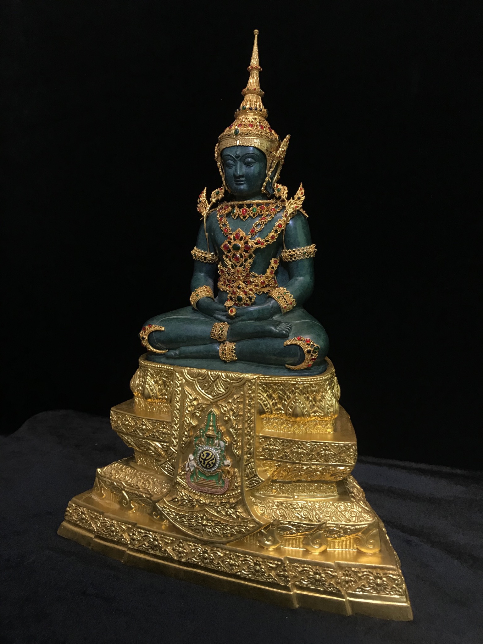 พระแก้วมรกต(จำลอง)ลอยองค์ ขนาดหน้าตัก 5 นิ้ว ทรงเครื่องฤดูร้อน เนื้อโลหะเคลือบสีเขียว เครื่องทรงชุบทองลงยาสี ฐานเนื้อโลหะ ลงรักปิดทองคำ ประดิษฐานตราสัญลักษณ์ฉลองสิริราชสมบัติ ครบ 60 ปี