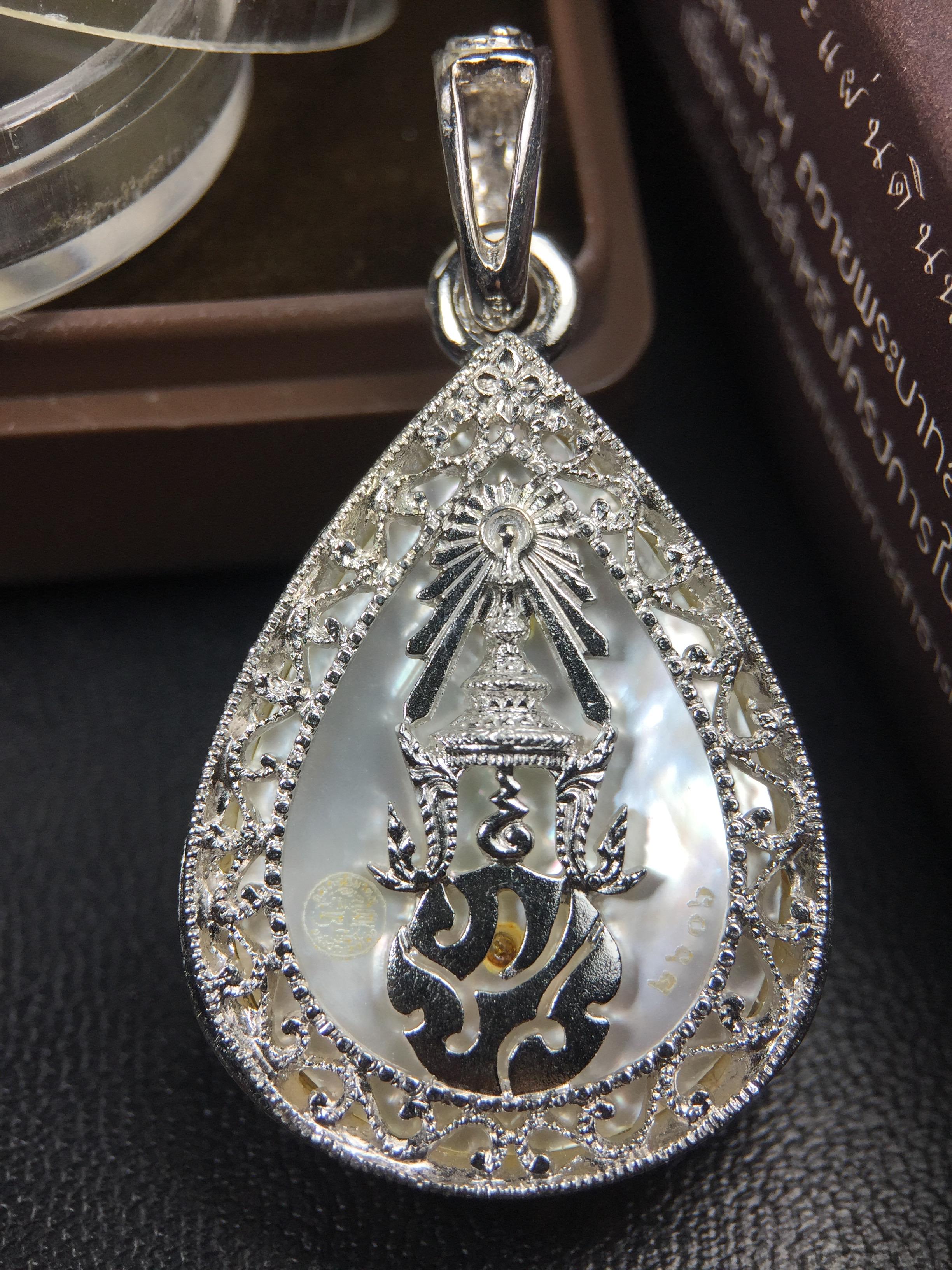 พระพุทธชินราช ภปร. โครงการ "เพราะแผ่นดินนี้ คือ แผ่นดินเกิด" ปี2548(รุ่นแรก) เหรียญทรงหยดน้ำ ขนาด 21 x 31 มม. เนื้อเงินสามกษัตริย์ องค์พระชุบสามกษัตริย์ ล้อมด้วยกรอบเงินชุบทองคำขาวสลักเสลาเป็นลวดลายละเอียดอ่อน ส่วนพื้นองค์พระเป็นเปลือกหอยมุข