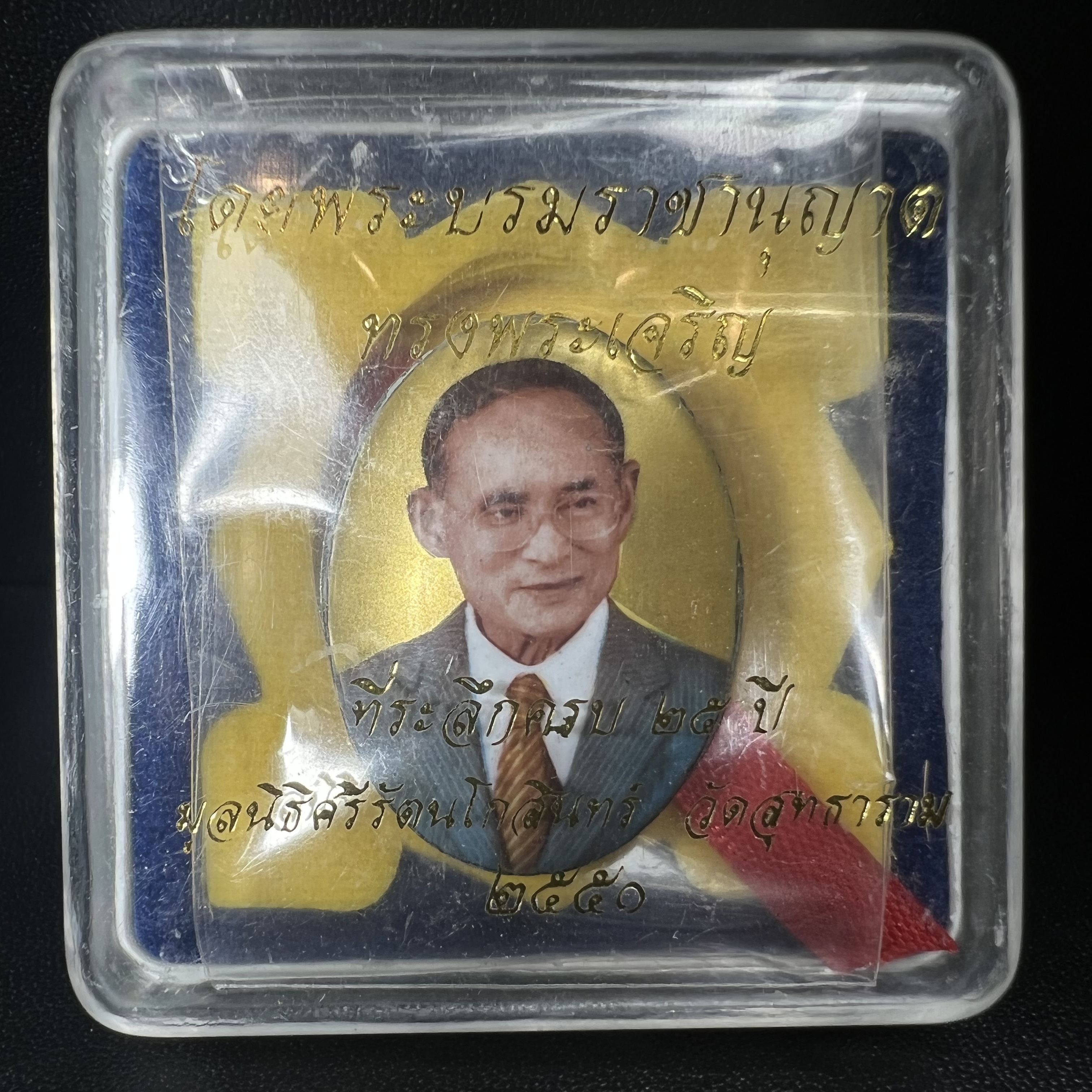 ล็อกเกตในหลวงรัชกาลที่9 ที่ระลึกครบ 25 ปี มูลนิธิศรีรัตนโกสินทร์ วัดสุทธาราม พ.ศ. 2550 พิมพ์ทรงวงรีรูปไข่เล็กฉากสีทอง หลังปิดแผ่นโลหะสีขาว(สแตนเลส)ฝังพระยอดธง(นิยม)