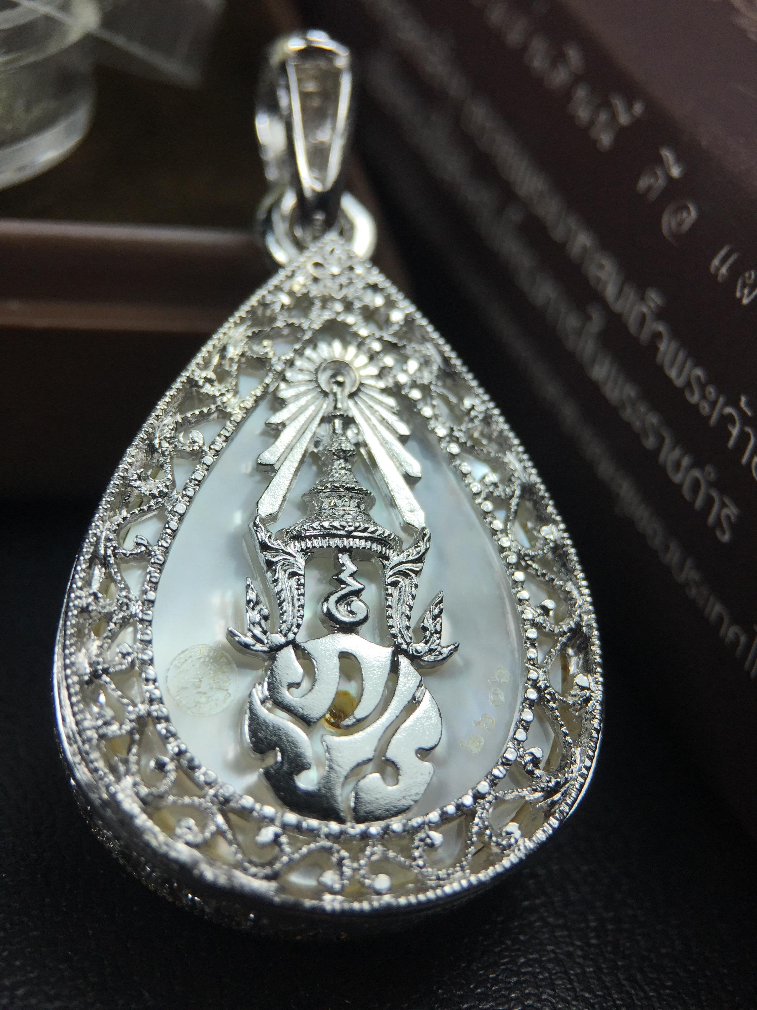 พระพุทธชินราช ภปร. โครงการ "เพราะแผ่นดินนี้ คือ แผ่นดินเกิด" ปี2548(รุ่นแรก) เหรียญทรงหยดน้ำ ขนาด 21 x 31 มม. เนื้อเงินสามกษัตริย์ องค์พระชุบสามกษัตริย์ ล้อมด้วยกรอบเงินชุบทองคำขาวสลักเสลาเป็นลวดลายละเอียดอ่อน ส่วนพื้นองค์พระเป็นเปลือกหอยมุข