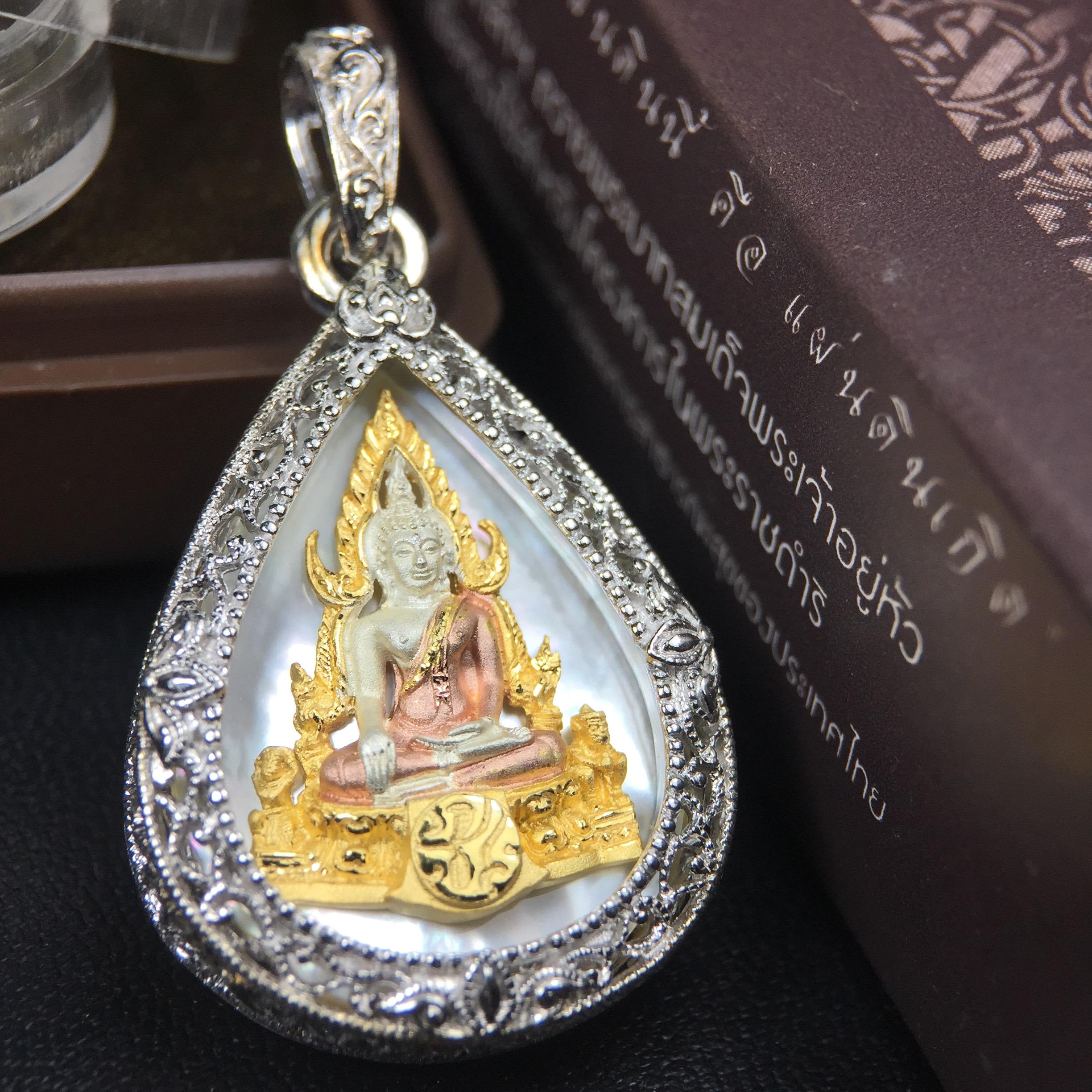 พระพุทธชินราช ภปร. โครงการ "เพราะแผ่นดินนี้ คือ แผ่นดินเกิด" ปี2548(รุ่นแรก) เหรียญทรงหยดน้ำ ขนาด 21 x 31 มม. เนื้อเงินสามกษัตริย์ องค์พระชุบสามกษัตริย์ ล้อมด้วยกรอบเงินชุบทองคำขาวสลักเสลาเป็นลวดลายละเอียดอ่อน ส่วนพื้นองค์พระเป็นเปลือกหอยมุข
