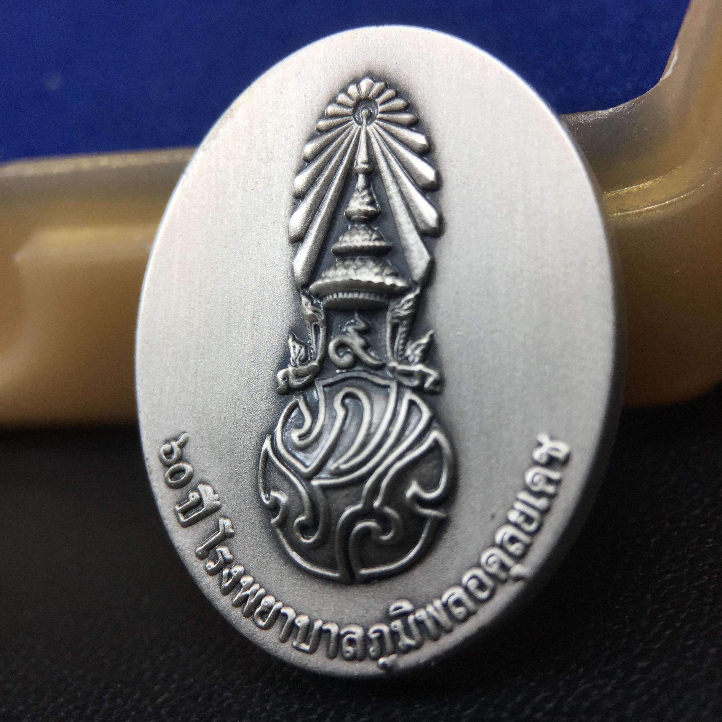 เหรียญพระบาทสมเด็จพระเจ้าอยู่หัวรัชกาลที่ 9 ภปร.(ใต้ร่มพระบารมี คุ้มเกล้า) 60ปี โรงพยาบาลภูมิพลฯ พ.ศ.2552 เนื้อเงิน (พิมพ์เล็กขนาด 25*20 มม.)สภาพสวยเดิมพร้อมกล่องบรรจุเดิม ตอกโค๊ดหมายเลขกำกับ เนื้อเงินหายากพบเจอน้อย