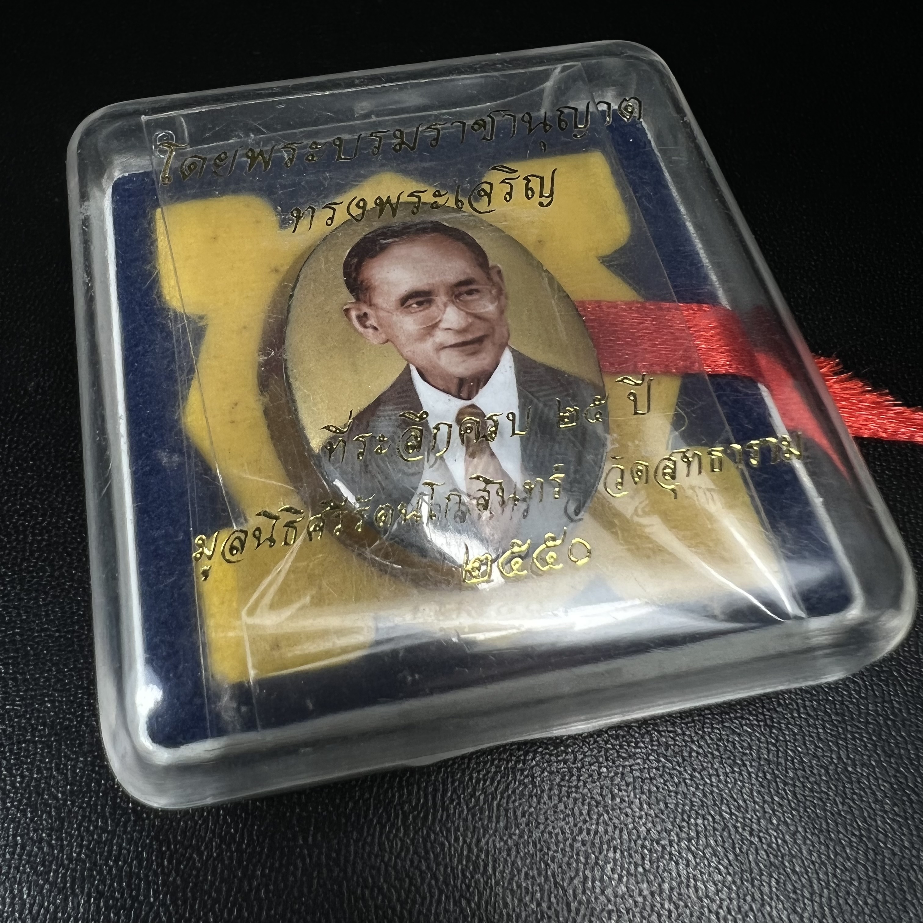 ล็อกเกตในหลวงรัชกาลที่9 ที่ระลึกครบ 25 ปี มูลนิธิศรีรัตนโกสินทร์ วัดสุทธาราม พ.ศ. 2550 พิมพ์ทรงวงรีรูปไข่เล็กฉากสีทอง หลังปิดแผ่นโลหะสีขาว(สแตนเลส)ฝังพระยอดธง(นิยม)