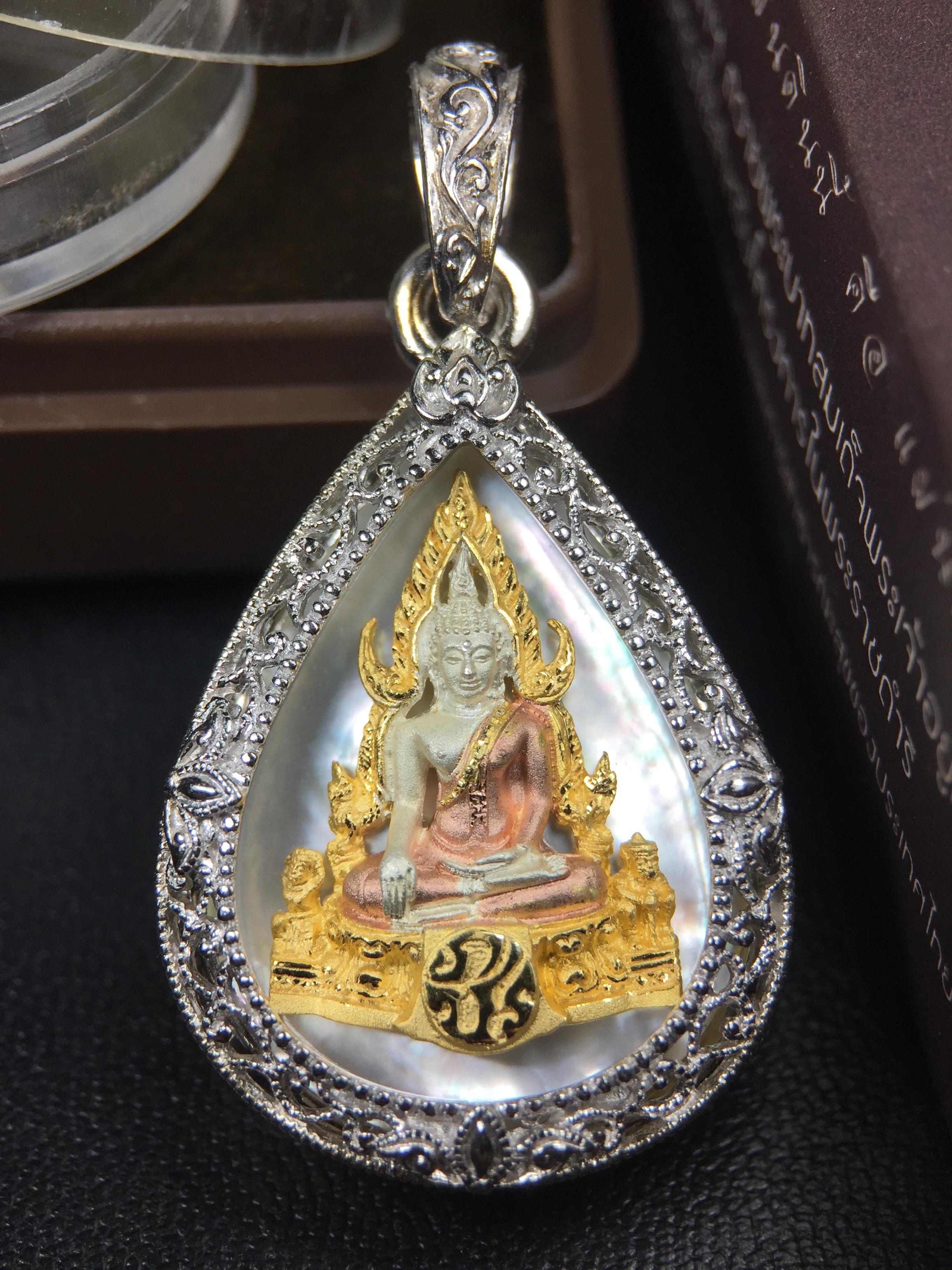 พระพุทธชินราช ภปร. โครงการ "เพราะแผ่นดินนี้ คือ แผ่นดินเกิด" ปี2548(รุ่นแรก) เหรียญทรงหยดน้ำ ขนาด 21 x 31 มม. เนื้อเงินสามกษัตริย์ องค์พระชุบสามกษัตริย์ ล้อมด้วยกรอบเงินชุบทองคำขาวสลักเสลาเป็นลวดลายละเอียดอ่อน ส่วนพื้นองค์พระเป็นเปลือกหอยมุข