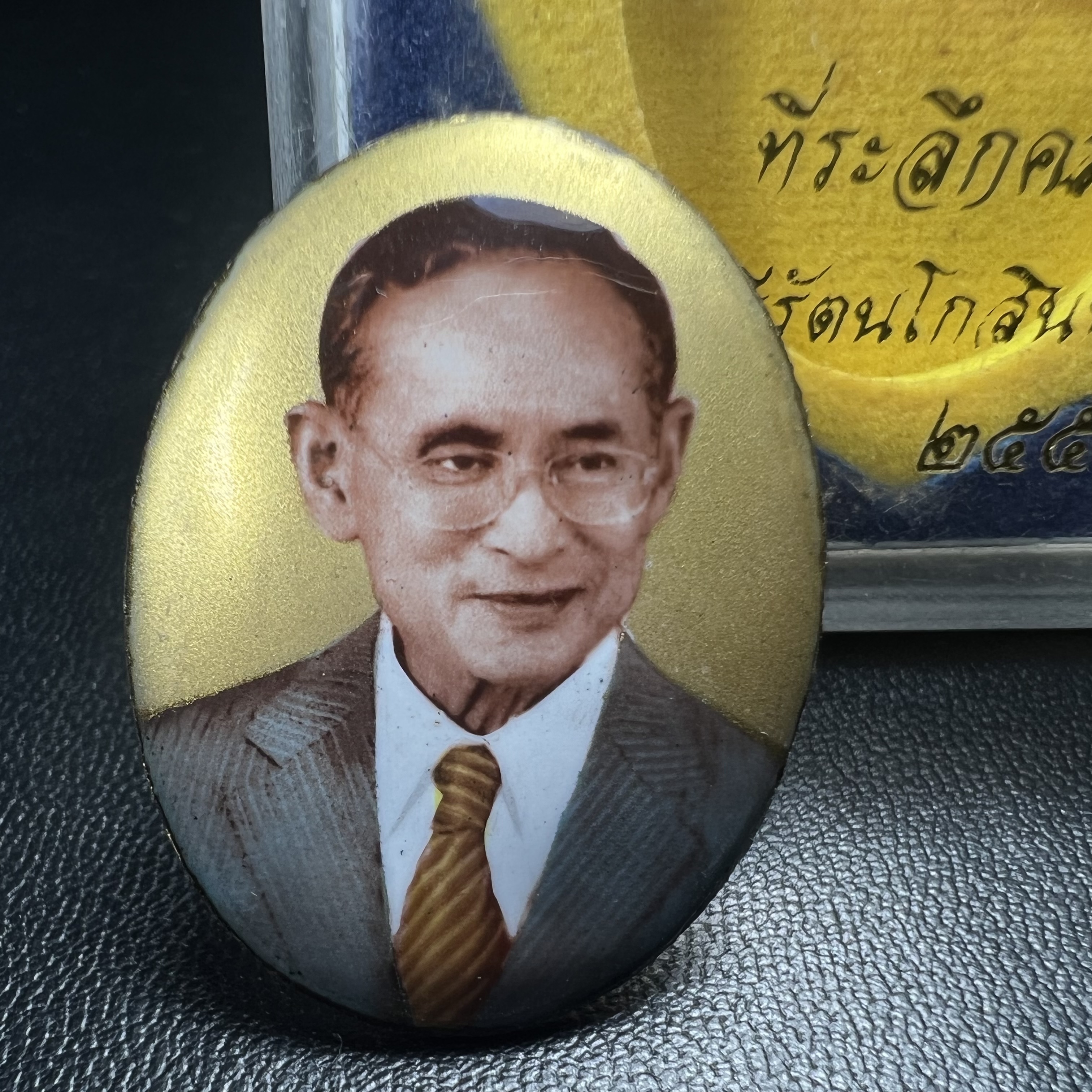 ล็อกเกตในหลวงรัชกาลที่9 ที่ระลึกครบ 25 ปี มูลนิธิศรีรัตนโกสินทร์ วัดสุทธาราม พ.ศ. 2550 พิมพ์ทรงวงรีรูปไข่เล็กฉากสีทอง หลังปิดแผ่นโลหะสีขาว(สแตนเลส)ฝังพระยอดธง(นิยม)