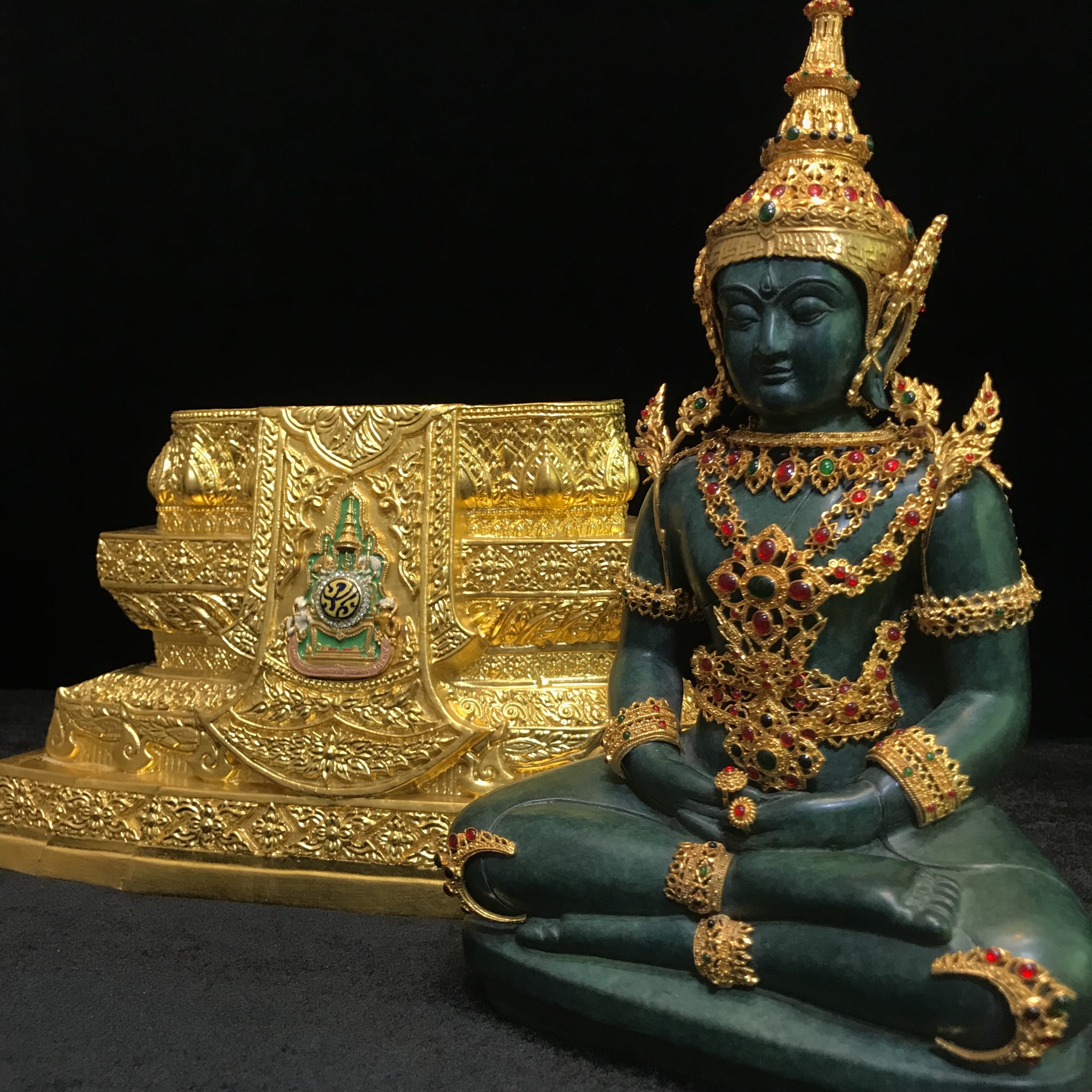 พระแก้วมรกต(จำลอง)ลอยองค์ ขนาดหน้าตัก 5 นิ้ว ทรงเครื่องฤดูร้อน เนื้อโลหะเคลือบสีเขียว เครื่องทรงชุบทองลงยาสี ฐานเนื้อโลหะ ลงรักปิดทองคำ ประดิษฐานตราสัญลักษณ์ฉลองสิริราชสมบัติ ครบ 60 ปี