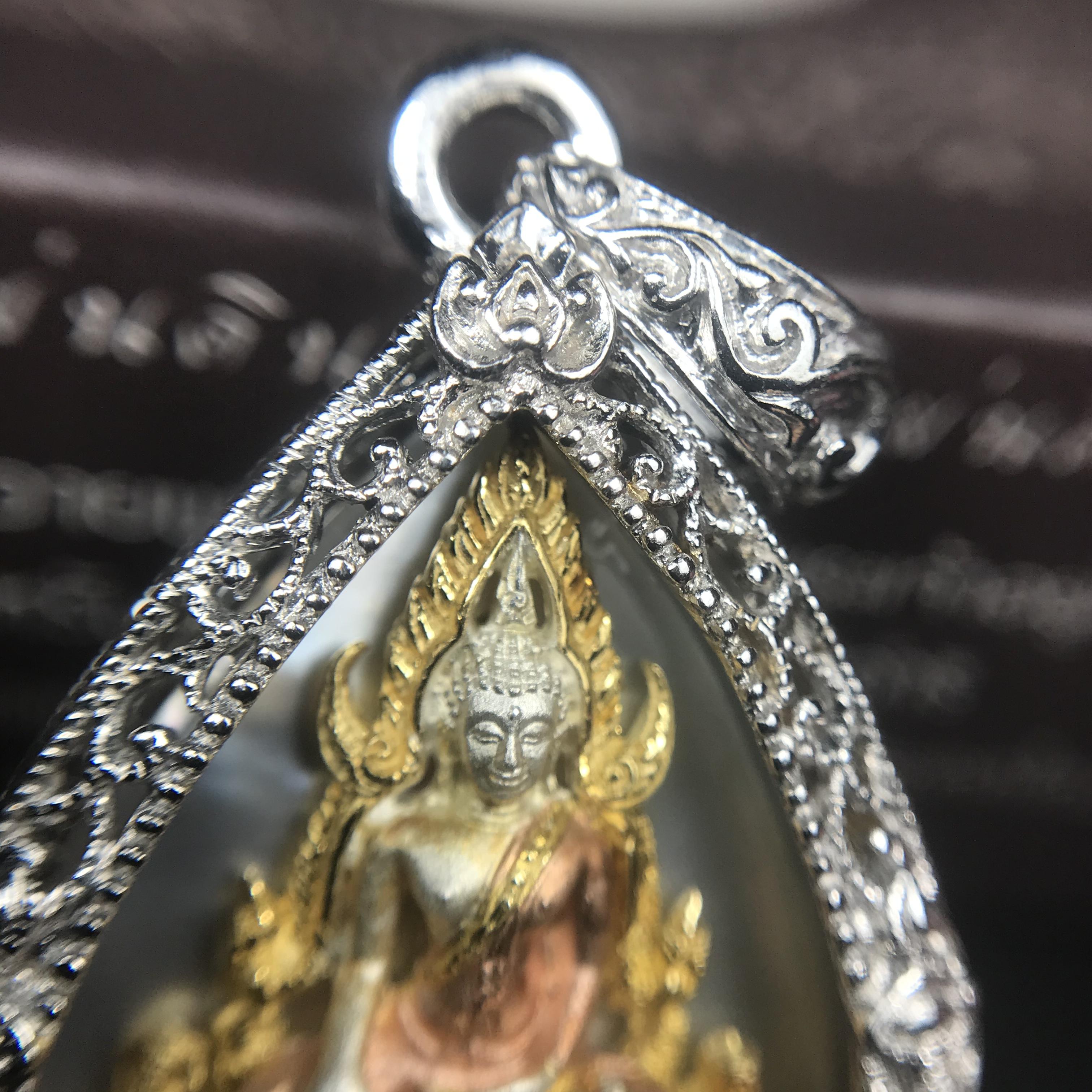 พระพุทธชินราช ภปร. โครงการ "เพราะแผ่นดินนี้ คือ แผ่นดินเกิด" ปี2548(รุ่นแรก) เหรียญทรงหยดน้ำ ขนาด 21 x 31 มม. เนื้อเงินสามกษัตริย์ องค์พระชุบสามกษัตริย์ ล้อมด้วยกรอบเงินชุบทองคำขาวสลักเสลาเป็นลวดลายละเอียดอ่อน ส่วนพื้นองค์พระเป็นเปลือกหอยมุข