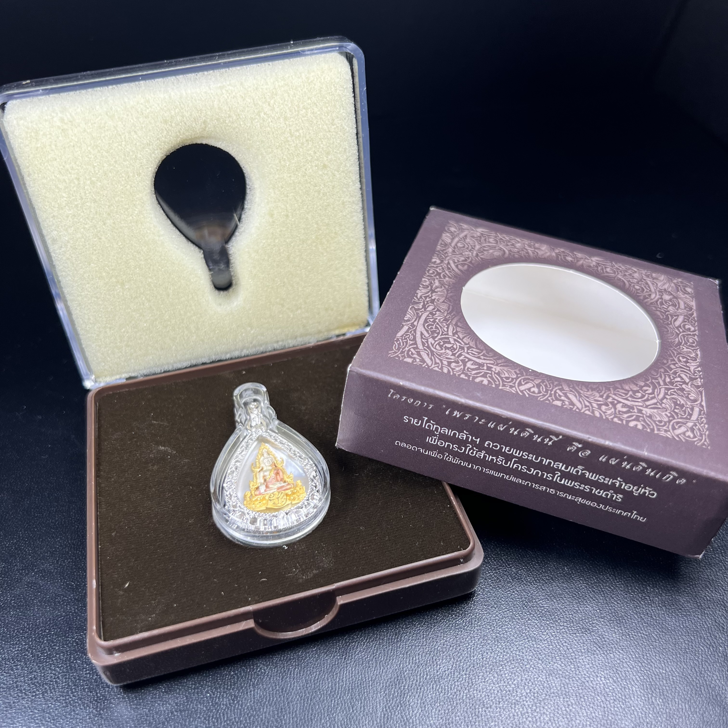 พระพุทธชินราช ภปร. โครงการ "เพราะแผ่นดินนี้ คือ แผ่นดินเกิด" ปี2548(รุ่นแรก) เหรียญทรงหยดน้ำ ขนาด 21 x 31 มม. เนื้อเงินสามกษัตริย์ องค์พระชุบสามกษัตริย์ ล้อมด้วยกรอบเงินชุบทองคำขาวสลักเสลาเป็นลวดลายละเอียดอ่อน ส่วนพื้นองค์พระเป็นเปลือกหอยมุข