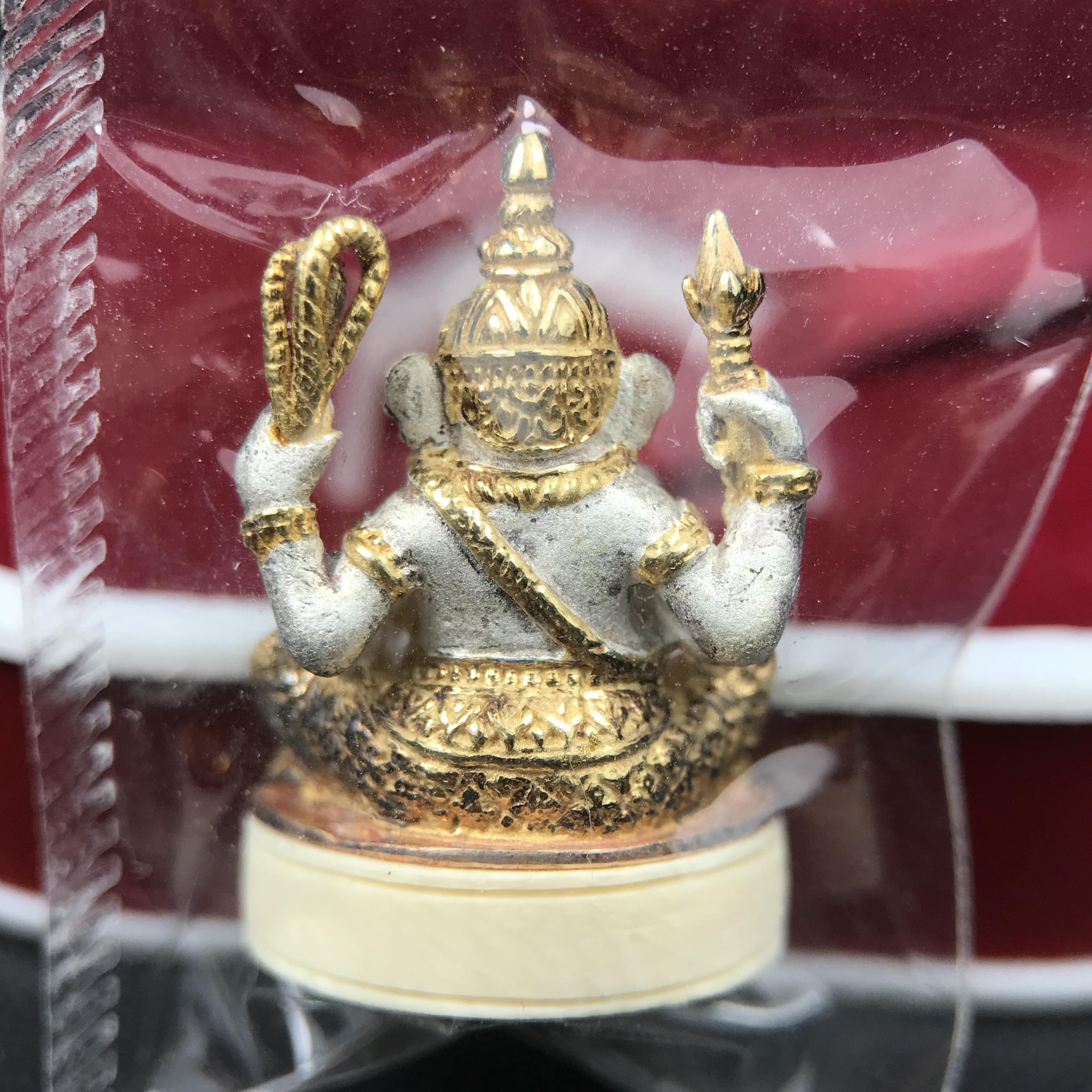พระพิฆเนศวร รุ่น คชสารหมื่นปี รูปเหมือนพระพิฆเนศวรนั่งประทานพรฐานงาช้างแมมมอสขนาดห้อยคอ เนื้อเงินชุบสามกษัตริย์ขัดเงา พิมพ์เล็ก สูง 2.2 ซม. ฝังพลอยทับทิมแท้ พิธีมหาเทวาภิเษก ณ. เทวสถานโบสถ์พราหมณ์ (เสาชิงช้า) โดยเกจิคณาจารย์ทั่วประทศ ปี 2545(หมายเลข ๓๐)