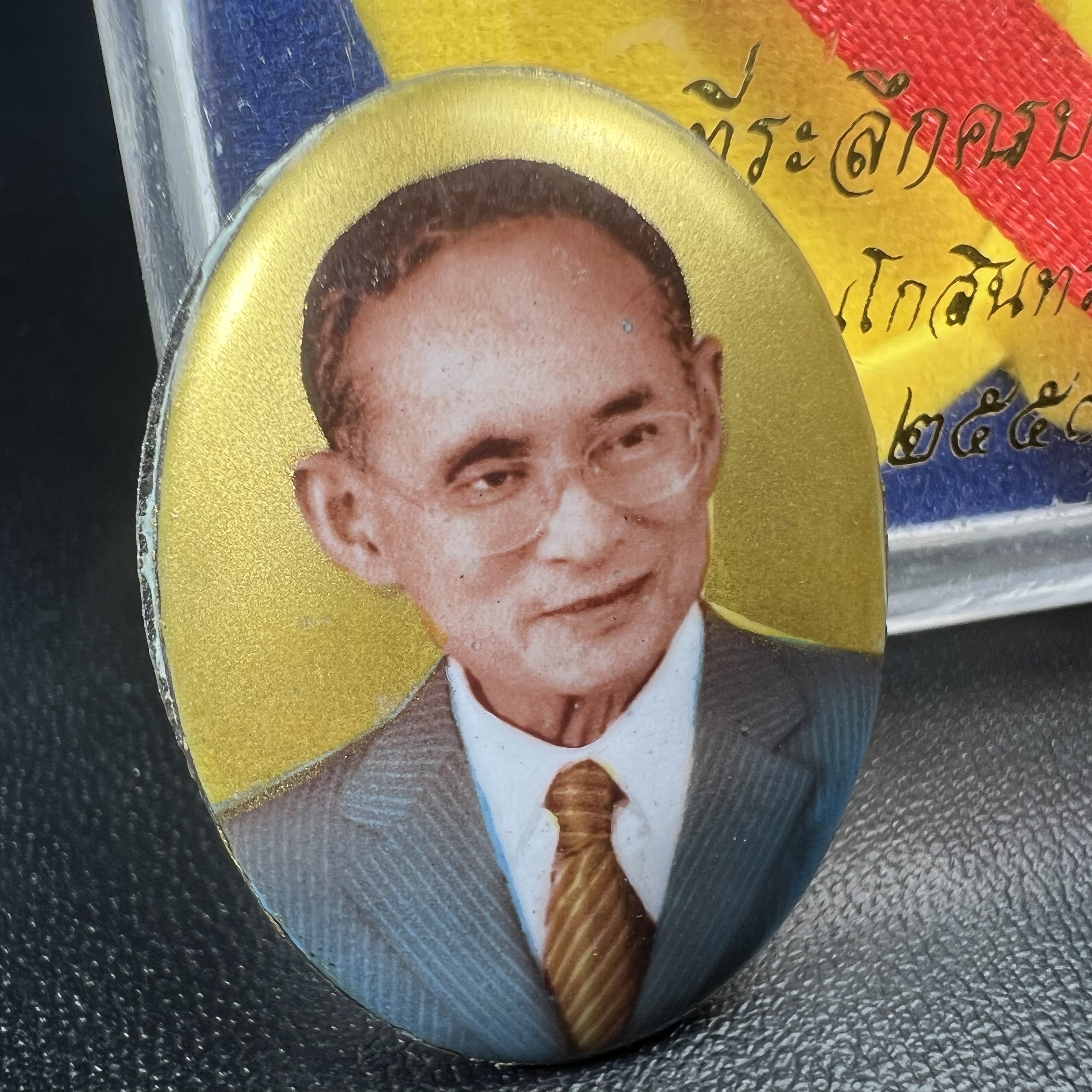 ล็อกเกตในหลวงรัชกาลที่9 ที่ระลึกครบ 25 ปี มูลนิธิศรีรัตนโกสินทร์ วัดสุทธาราม พ.ศ. 2550 พิมพ์ทรงวงรีรูปไข่เล็กฉากสีทอง หลังปิดแผ่นโลหะสีขาว(สแตนเลส)ฝังพระยอดธง(นิยม)