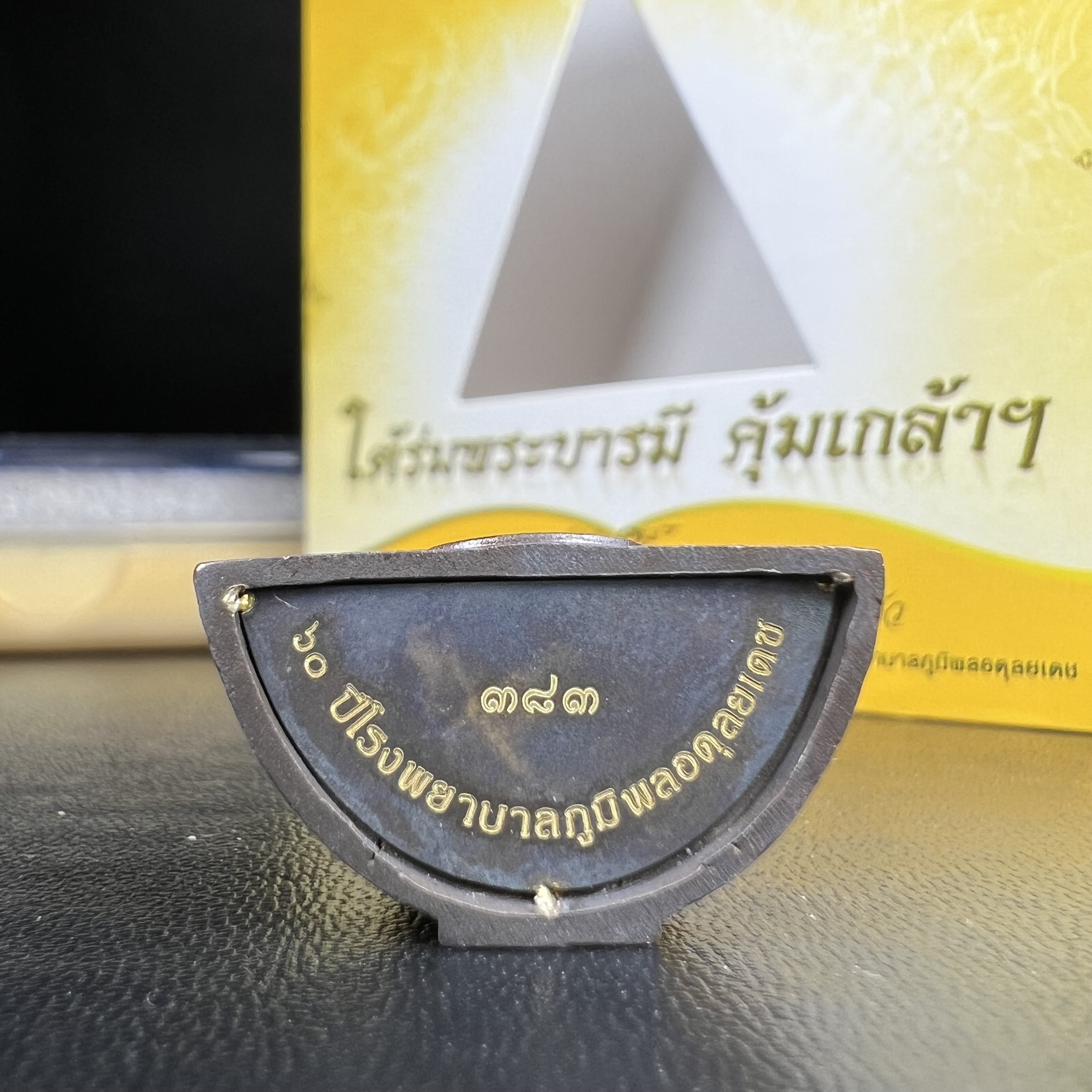 พระพุทธรูปคุ้มเกล้าฯ ภปร.(ใต้ร่มพระบารมี คุ้มเกล้า) 60ปี โรงพยาบาลภูมิพลฯ พ.ศ.2552 เนื้อนวโลหะ รมดำ(พิมพ์ใหญ่ขนาด 35.5*24 มม.)สภาพสวยเดิมพร้อมกล่องบรรจุเดิม ตอกโค๊ดหมายเลขกำกับ