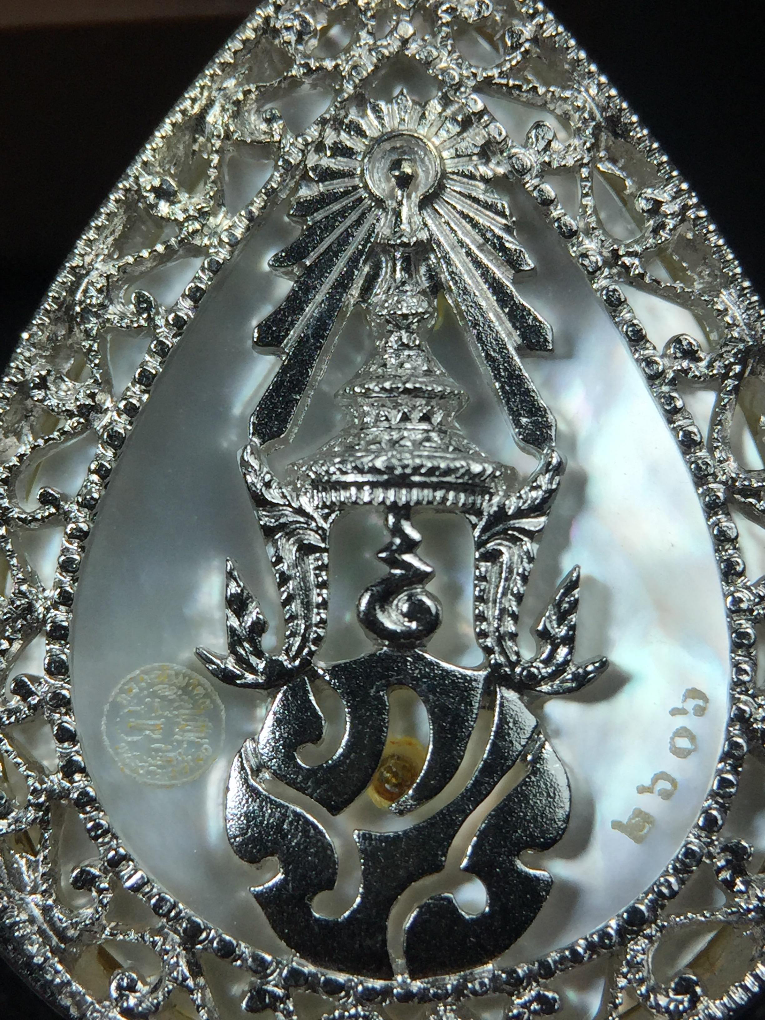 พระพุทธชินราช ภปร. โครงการ "เพราะแผ่นดินนี้ คือ แผ่นดินเกิด" ปี2548(รุ่นแรก) เหรียญทรงหยดน้ำ ขนาด 21 x 31 มม. เนื้อเงินสามกษัตริย์ องค์พระชุบสามกษัตริย์ ล้อมด้วยกรอบเงินชุบทองคำขาวสลักเสลาเป็นลวดลายละเอียดอ่อน ส่วนพื้นองค์พระเป็นเปลือกหอยมุข