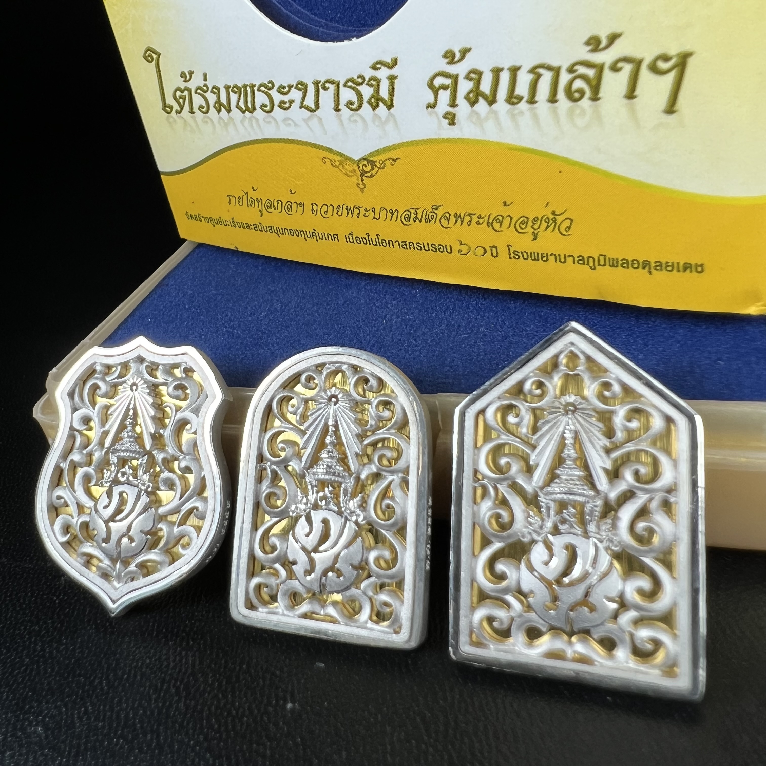 พระพุทธรูปคุ้มเกล้าฯ ภปร.(ใต้ร่มพระบารมี คุ้มเกล้า) 60ปี รพ.ภูมิพลฯ พ.ศ.2552 เหรียญเนื้อเงิน ชุบทองคำขาว(พิมพ์ รูปอาร์ม+รูปใบมะขาม+รูปห้าเหลี่ยม)(1ชุด 3 พิมพ์ ครบทุกแบบที่จัดสร้าง)1 ใน 5000 เหรียญ ครบชุดหายาก