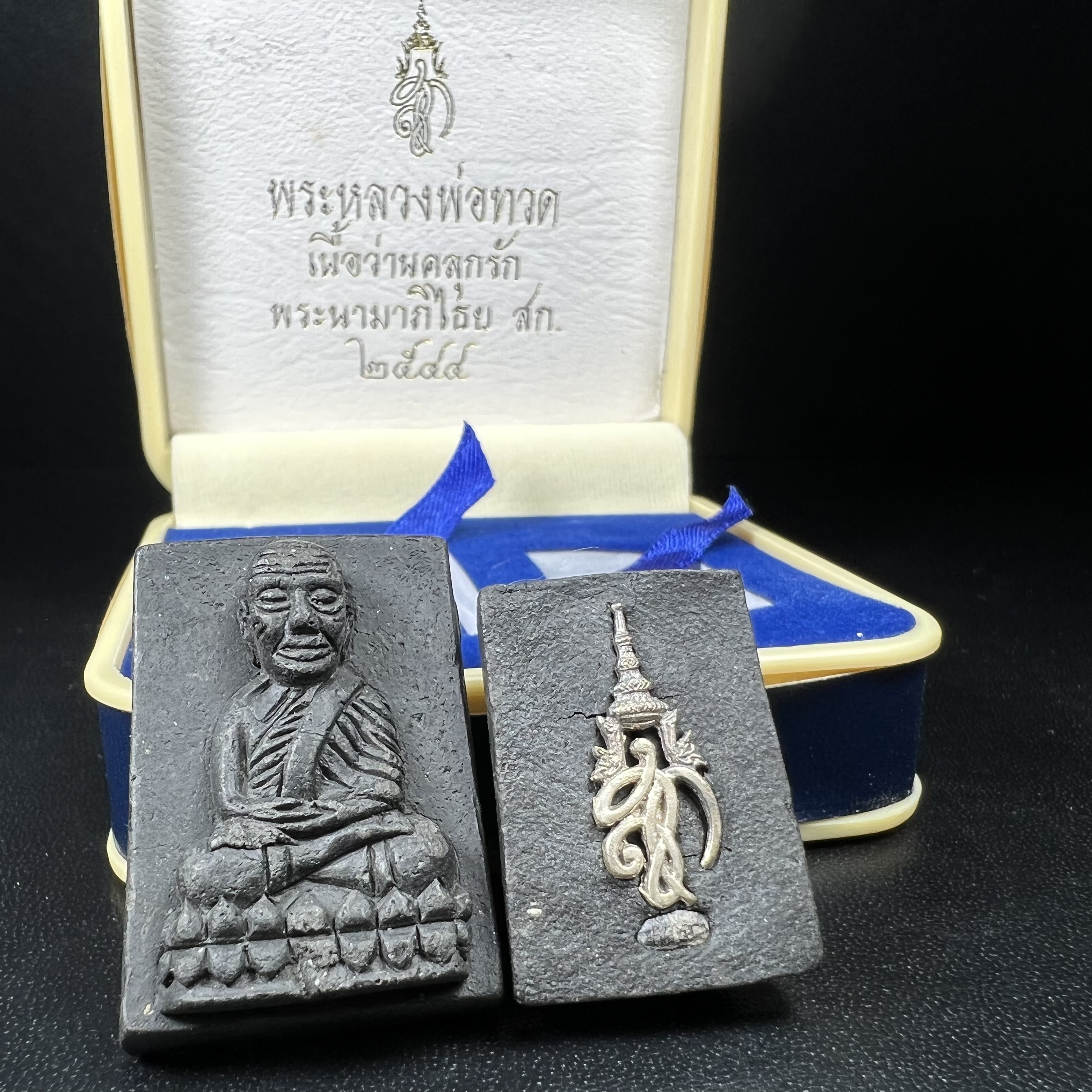 พระหลวงพ่อทวด พระนามาภิไธย สก. ปี2544(รุ่นแรก) เนื้อว่านคลุกรัก พิมพ์พิเศษหลังฝังข้าวสารดำ ชุดหลังพระนามาภิไธย สก. เนื้อเงิน(1ชุด 2องค์ พิมพ์ใหญ่สี่เหลี่ยม+พิมพ์เล็กพระรอดสี่เหลี่ยม)(1ใน5000 ชุด)พร้อมกล่องบรรจุเดิมหายาก