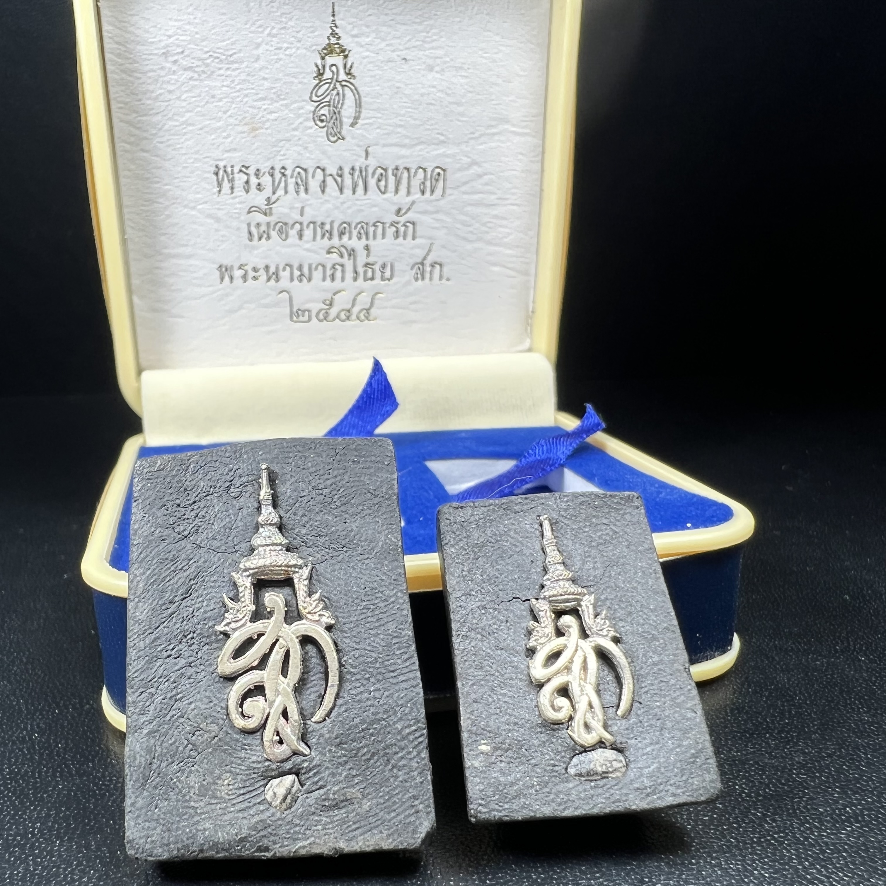 พระหลวงพ่อทวด พระนามาภิไธย สก. ปี2544(รุ่นแรก) เนื้อว่านคลุกรัก พิมพ์พิเศษหลังฝังข้าวสารดำ ชุดหลังพระนามาภิไธย สก. เนื้อเงิน(1ชุด 2องค์ พิมพ์ใหญ่สี่เหลี่ยม+พิมพ์เล็กพระรอดสี่เหลี่ยม)(1ใน5000 ชุด)พร้อมกล่องบรรจุเดิมหายาก