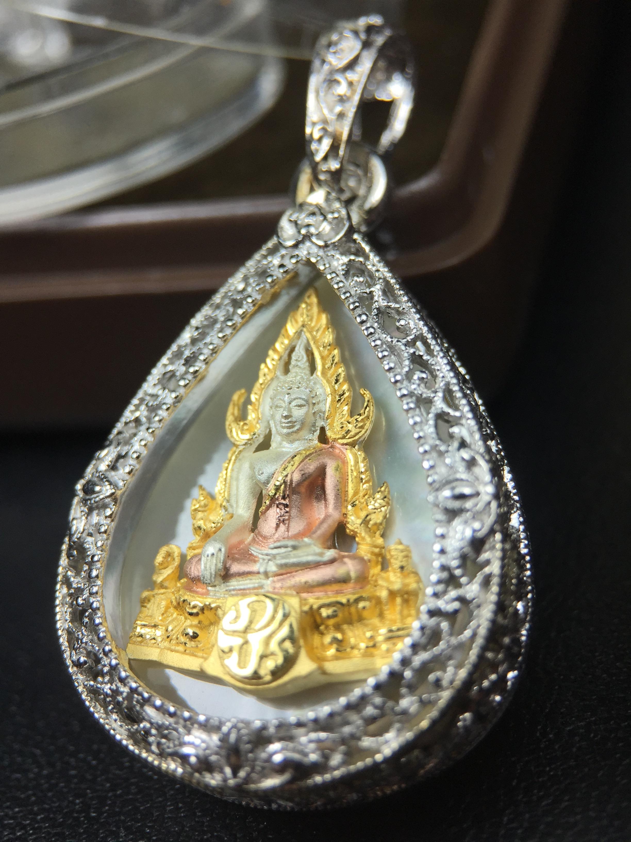 พระพุทธชินราช ภปร. โครงการ "เพราะแผ่นดินนี้ คือ แผ่นดินเกิด" ปี2548(รุ่นแรก) เหรียญทรงหยดน้ำ ขนาด 21 x 31 มม. เนื้อเงินสามกษัตริย์ องค์พระชุบสามกษัตริย์ ล้อมด้วยกรอบเงินชุบทองคำขาวสลักเสลาเป็นลวดลายละเอียดอ่อน ส่วนพื้นองค์พระเป็นเปลือกหอยมุข